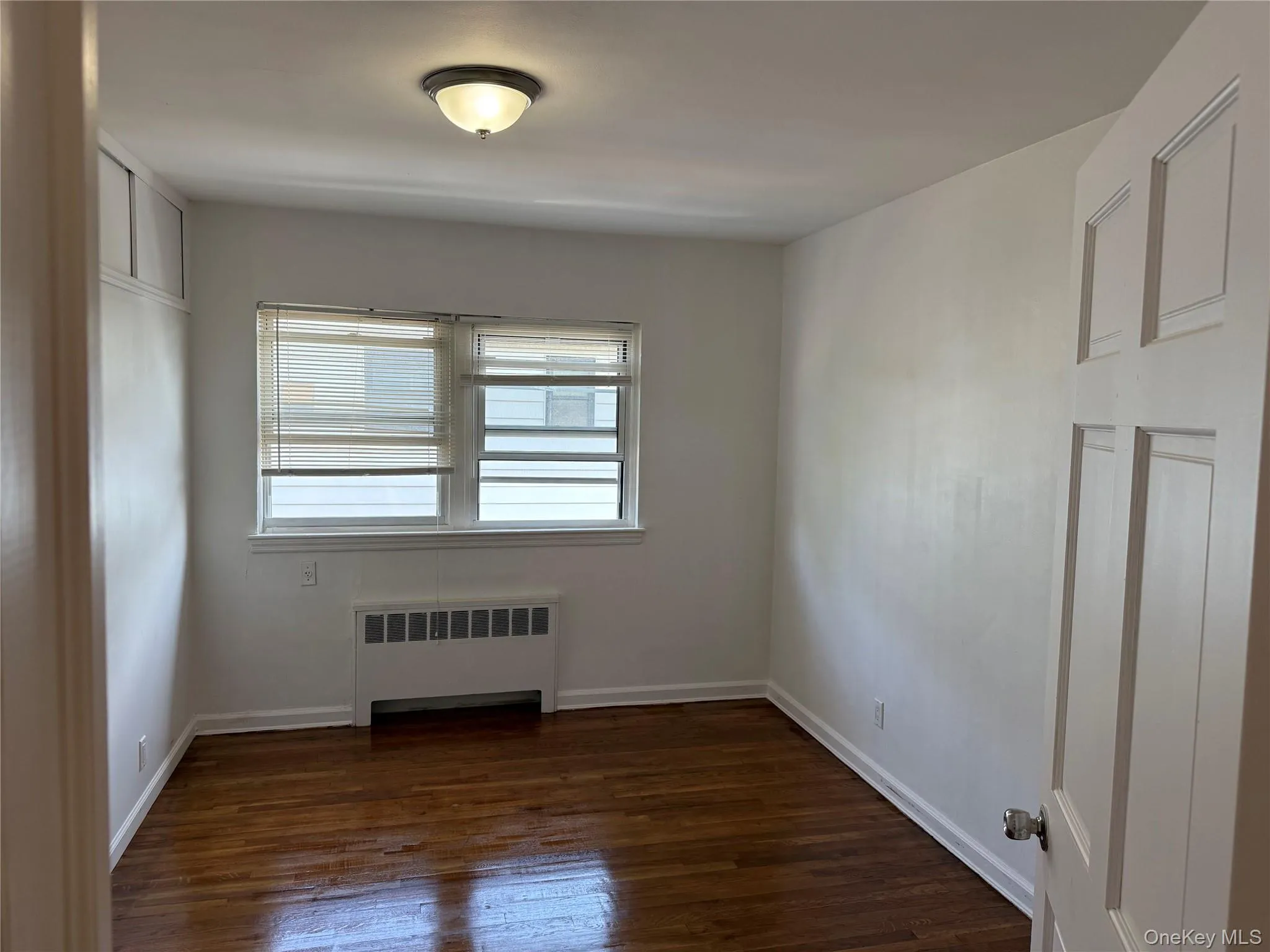 Empty room with radiator and dark wood finished floors Empty room with radiator and dark wood finished floors