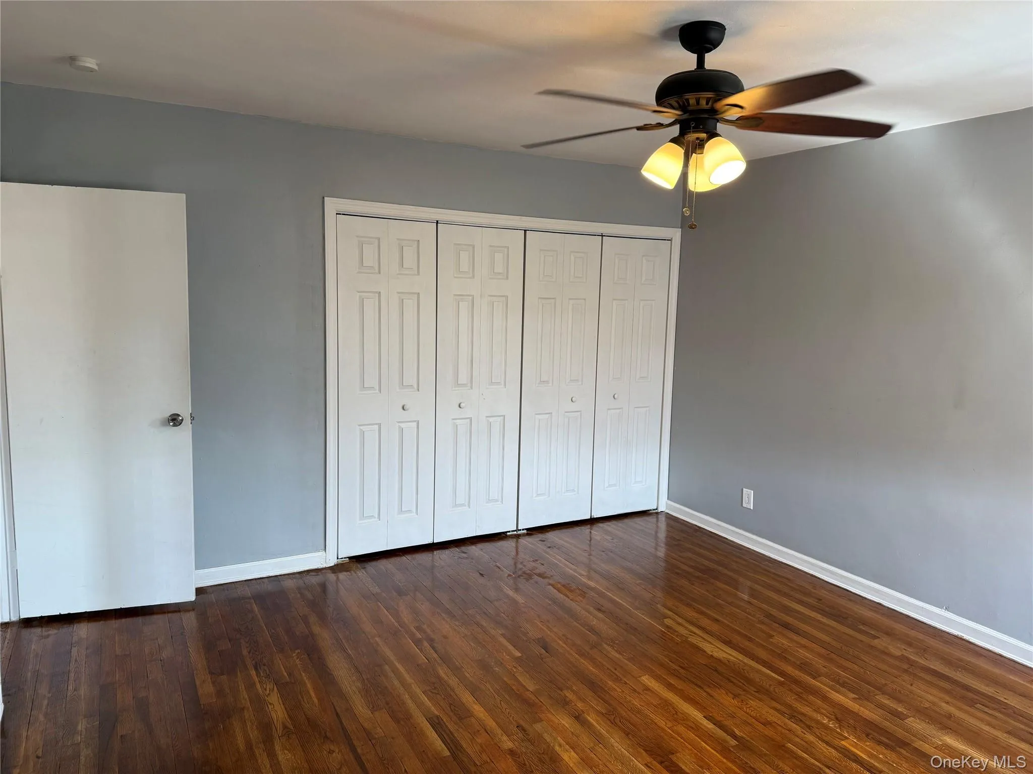 Unfurnished bedroom with dark wood-type flooring, a closet, and ceiling fan Unfurnished bedroom with dark wood-type flooring, a closet, and ceiling fan