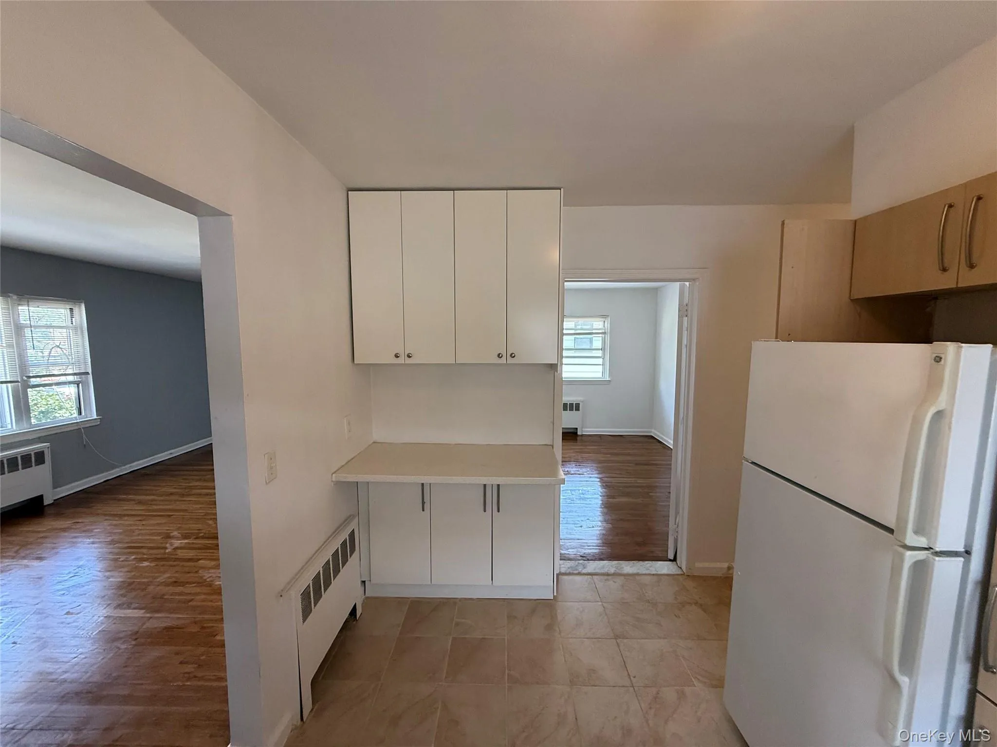 Kitchen featuring freestanding refrigerator, radiator heating unit, healthy amount of natural light, and light countertops Kitchen featuring freestanding refrigerator, radiator heating unit, healthy amount of natural light, and light countertops