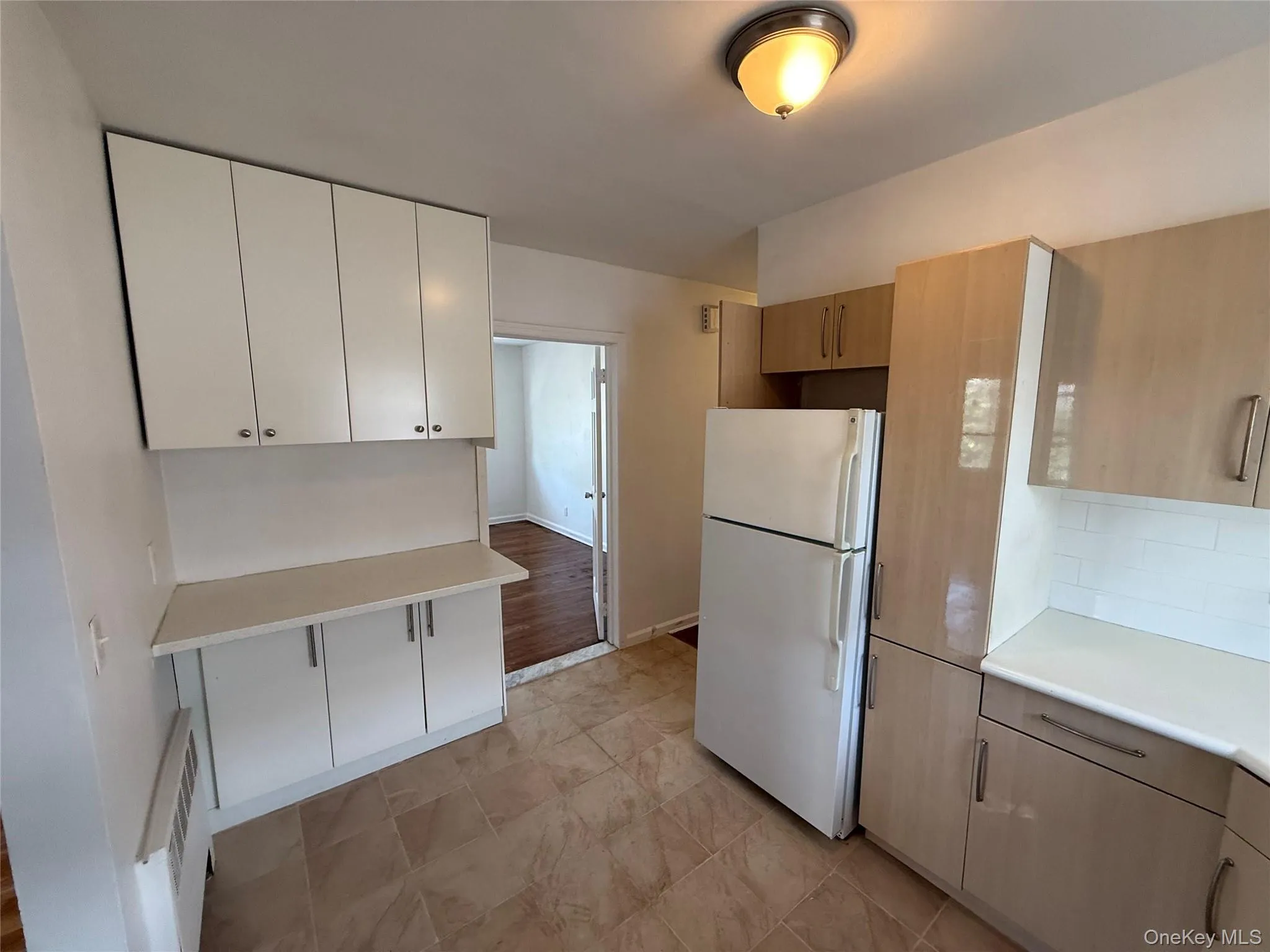 Kitchen featuring freestanding refrigerator, light countertops, and backsplash Kitchen featuring freestanding refrigerator, light countertops, and backsplash