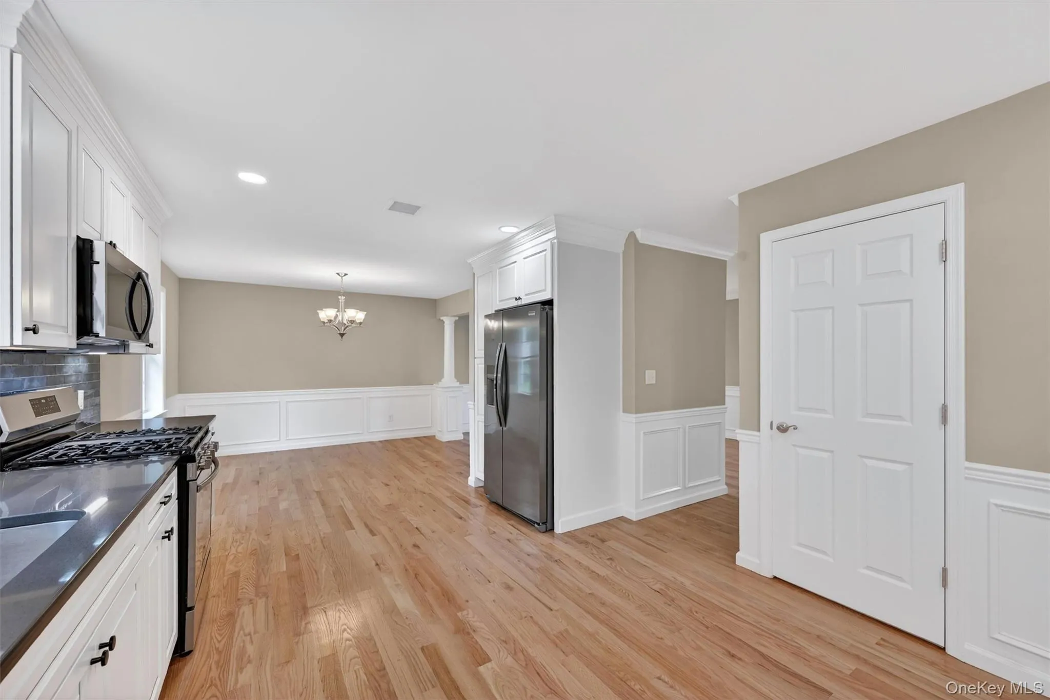 Kitchen featuring white cabinetry, stainless steel appliances, dark countertops, and a tiled backsplash Kitchen featuring white cabinetry, stainless steel appliances, dark countertops, and a tiled backsplash