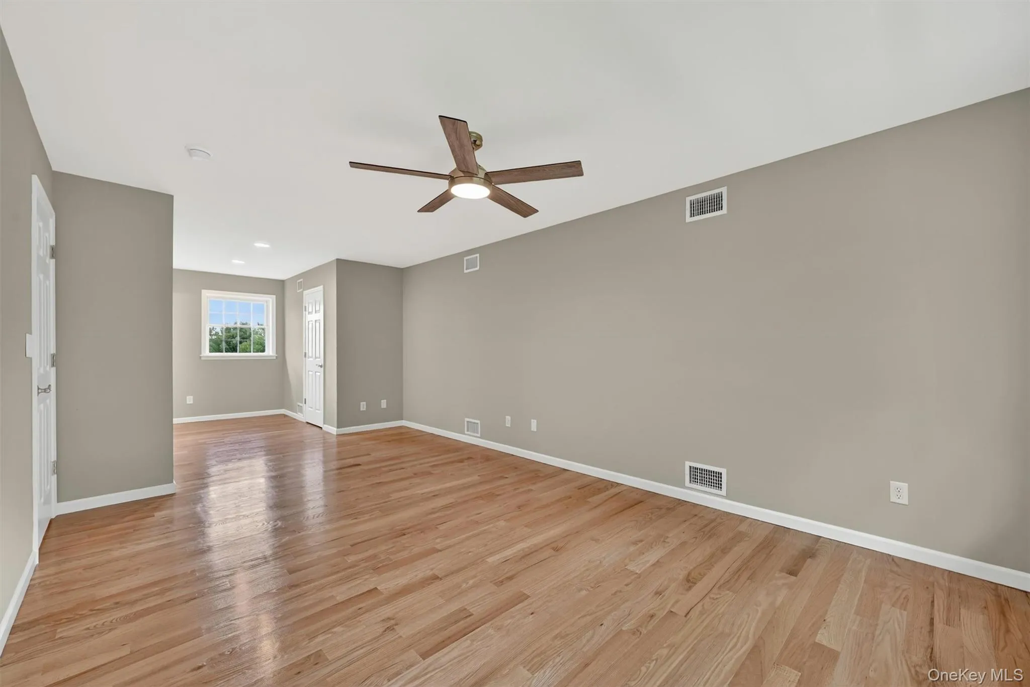 Spacious room featuring wood-finish flooring, a ceiling fan with integrated lighting, and recessed ceiling lights Spacious room featuring wood-finish flooring, a ceiling fan with integrated lighting, and recessed ceiling lights