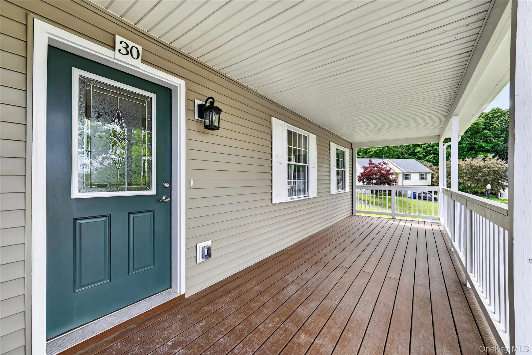 Covered front porch featuring wood-finish flooring, white railing, and beige siding Covered front porch featuring wood-finish flooring, white railing, and beige siding