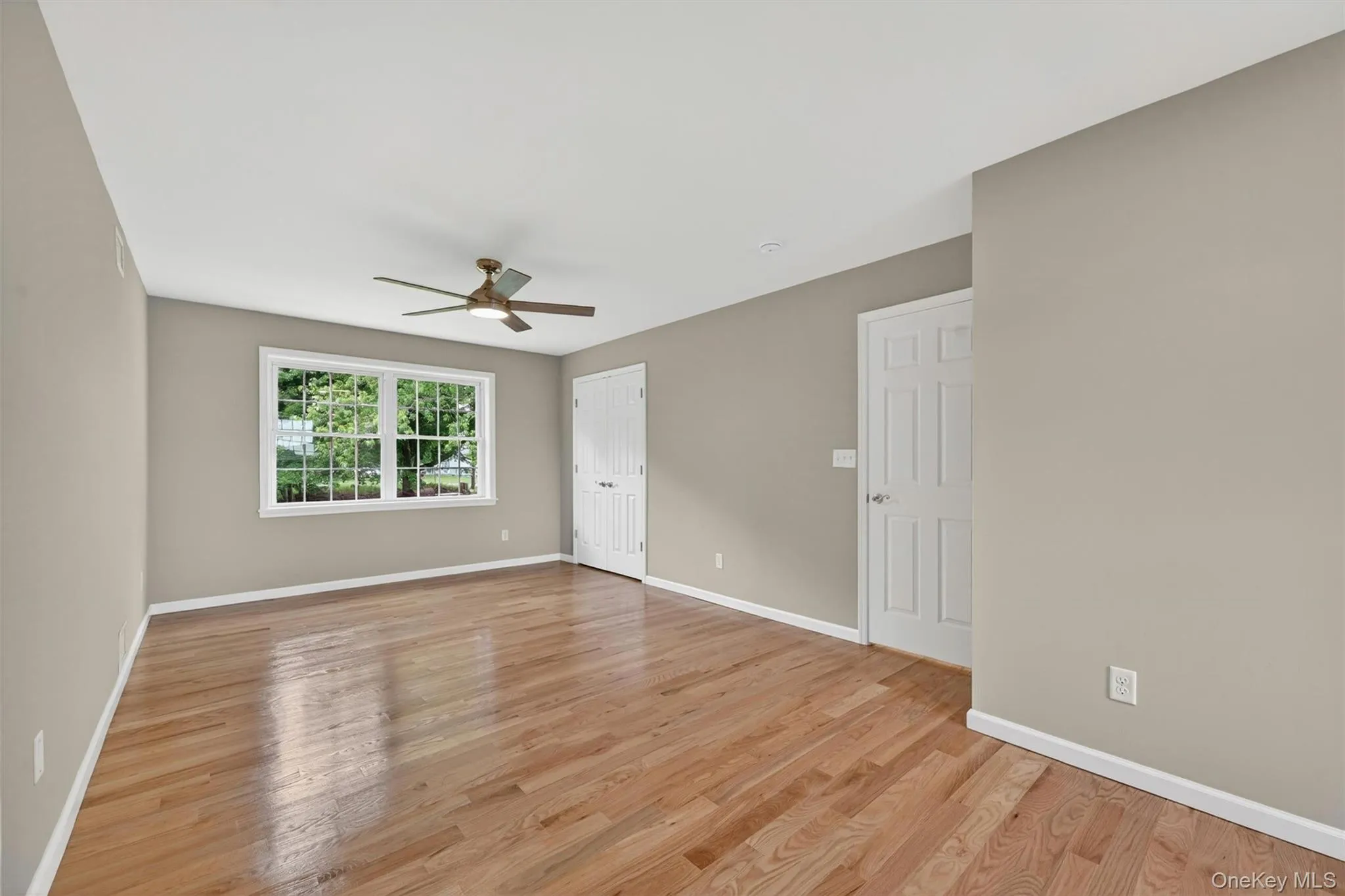 Spacious room featuring wood-finish flooring, a ceiling fan with integrated lighting, and recessed ceiling lights Spacious room featuring wood-finish flooring, a ceiling fan with integrated lighting, and recessed ceiling lights