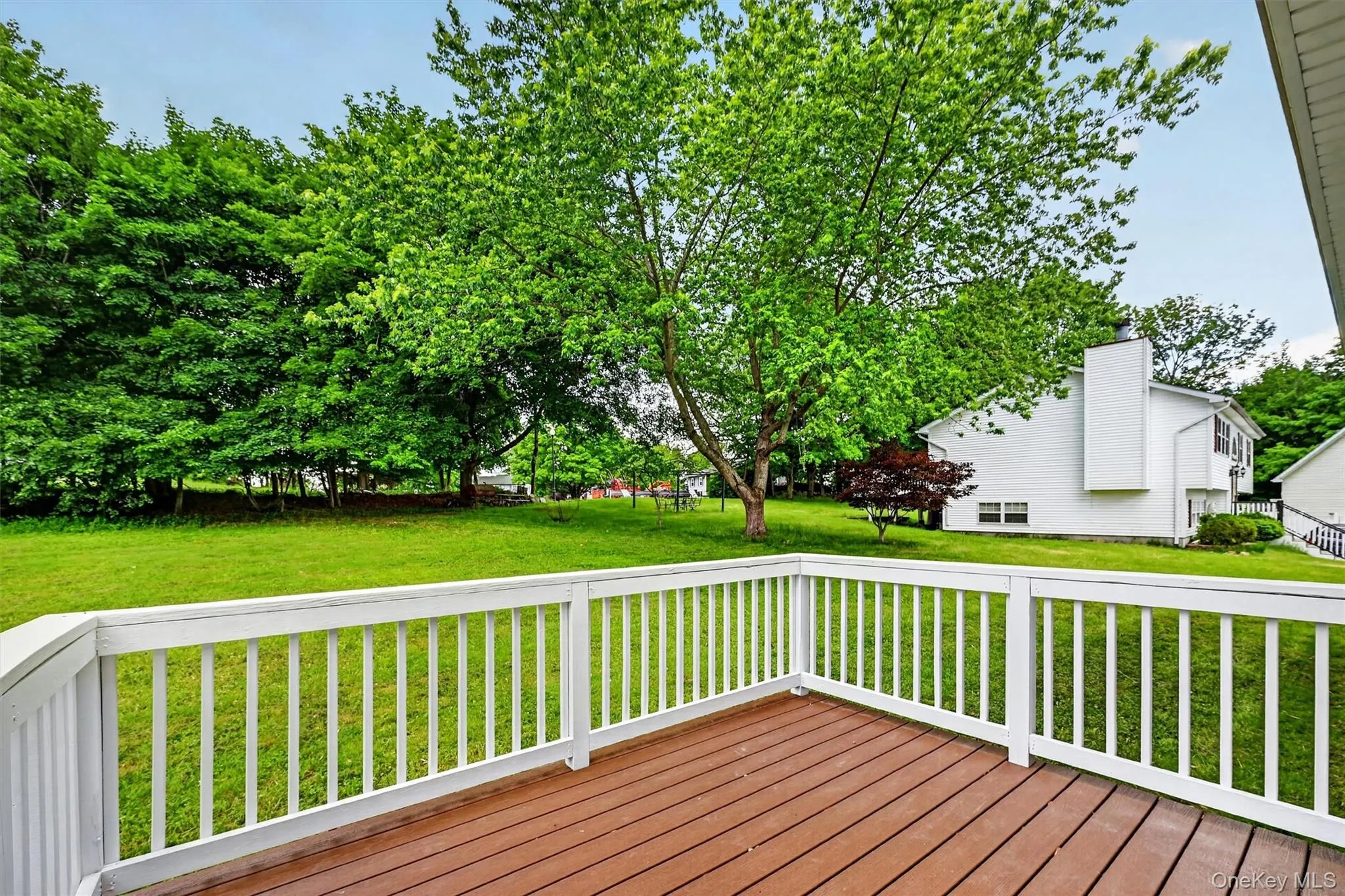 Spacious outdoor deck with wood-finish flooring and white railings Spacious outdoor deck with wood-finish flooring and white railings