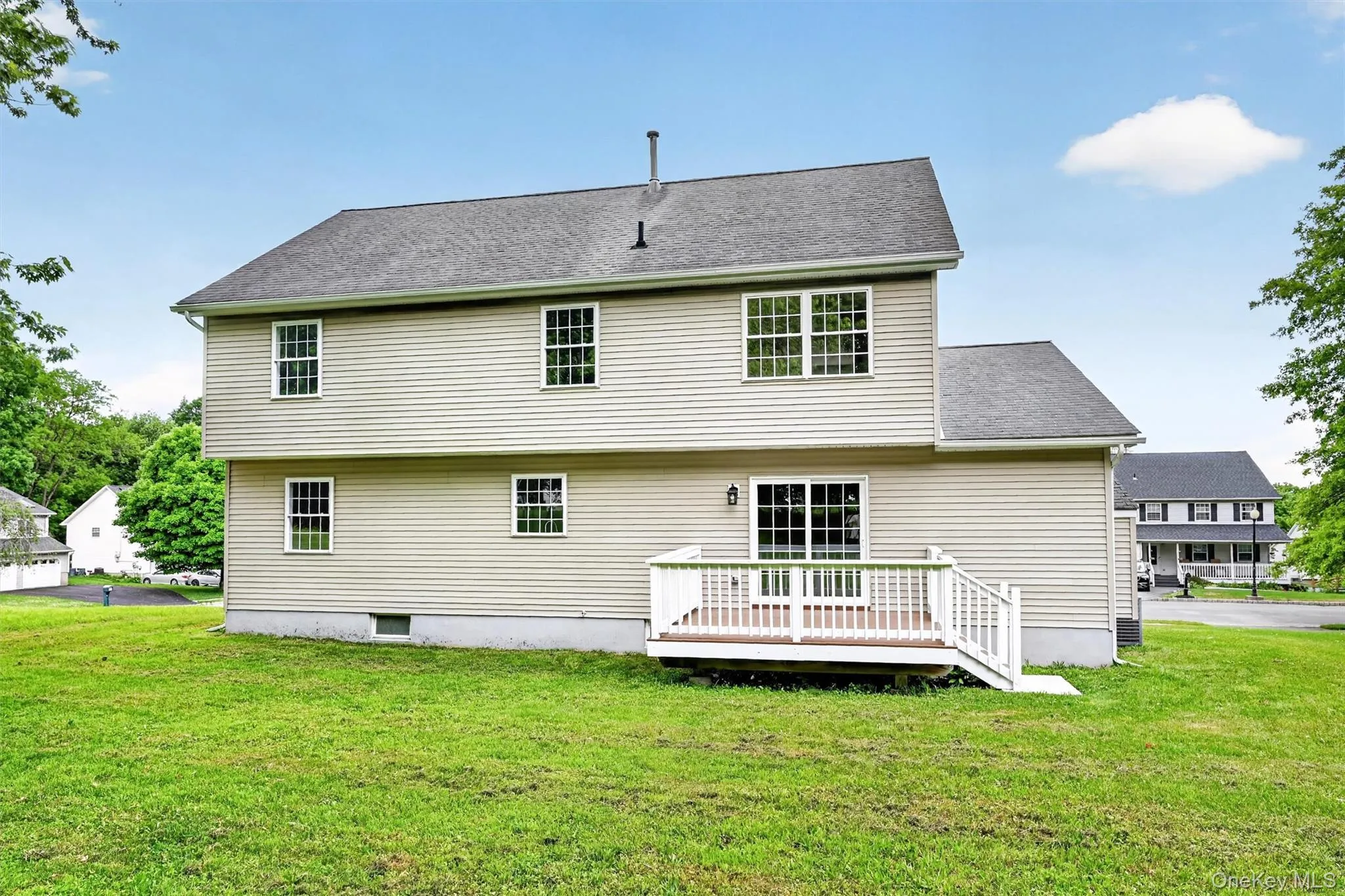 Rear exterior featuring beige horizontal siding and a gray asphalt shingle roof Rear exterior featuring beige horizontal siding and a gray asphalt shingle roof