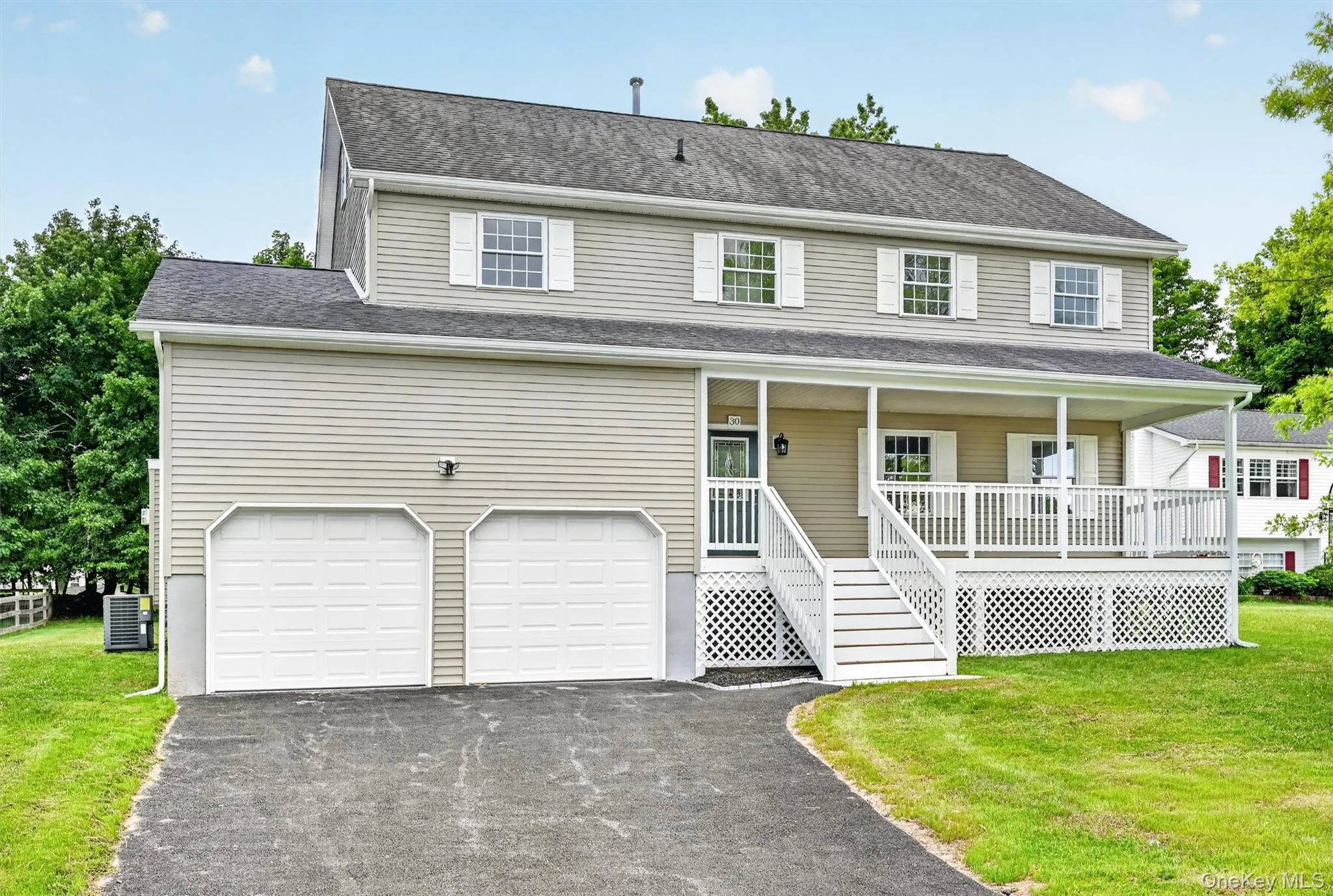 Two-story residence featuring light-toned siding and a prominent front porch with white railings and lattice detailing Two-story residence featuring light-toned siding and a prominent front porch with white railings and lattice detailing