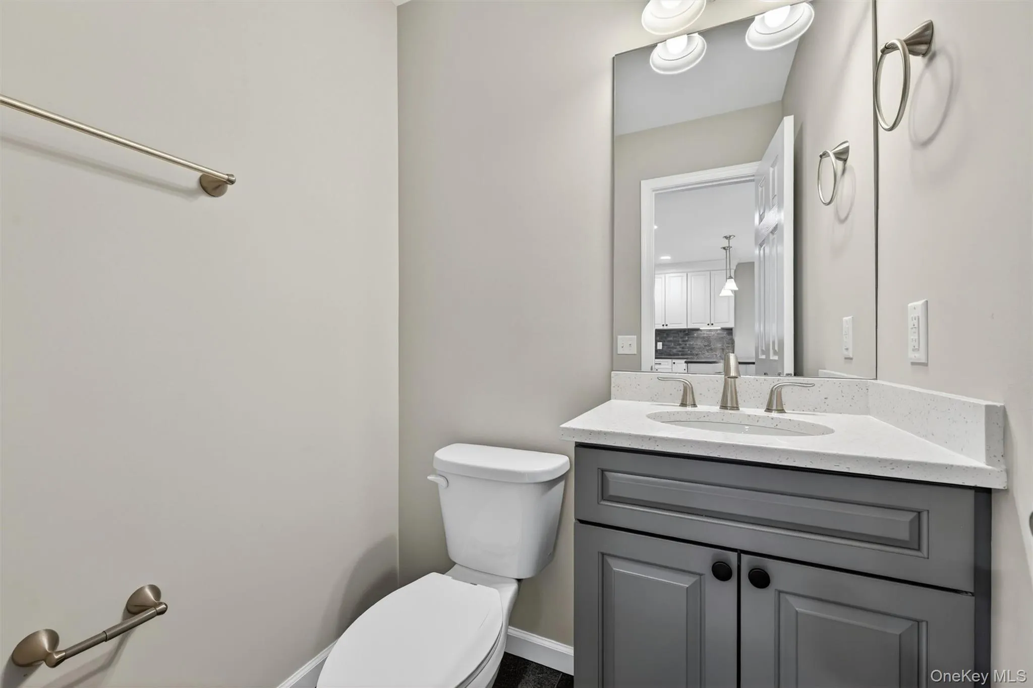 Bathroom featuring a gray vanity with an undermount sink, a light-toned countertop, and brushed nickel fixtures Bathroom featuring a gray vanity with an undermount sink, a light-toned countertop, and brushed nickel fixtures