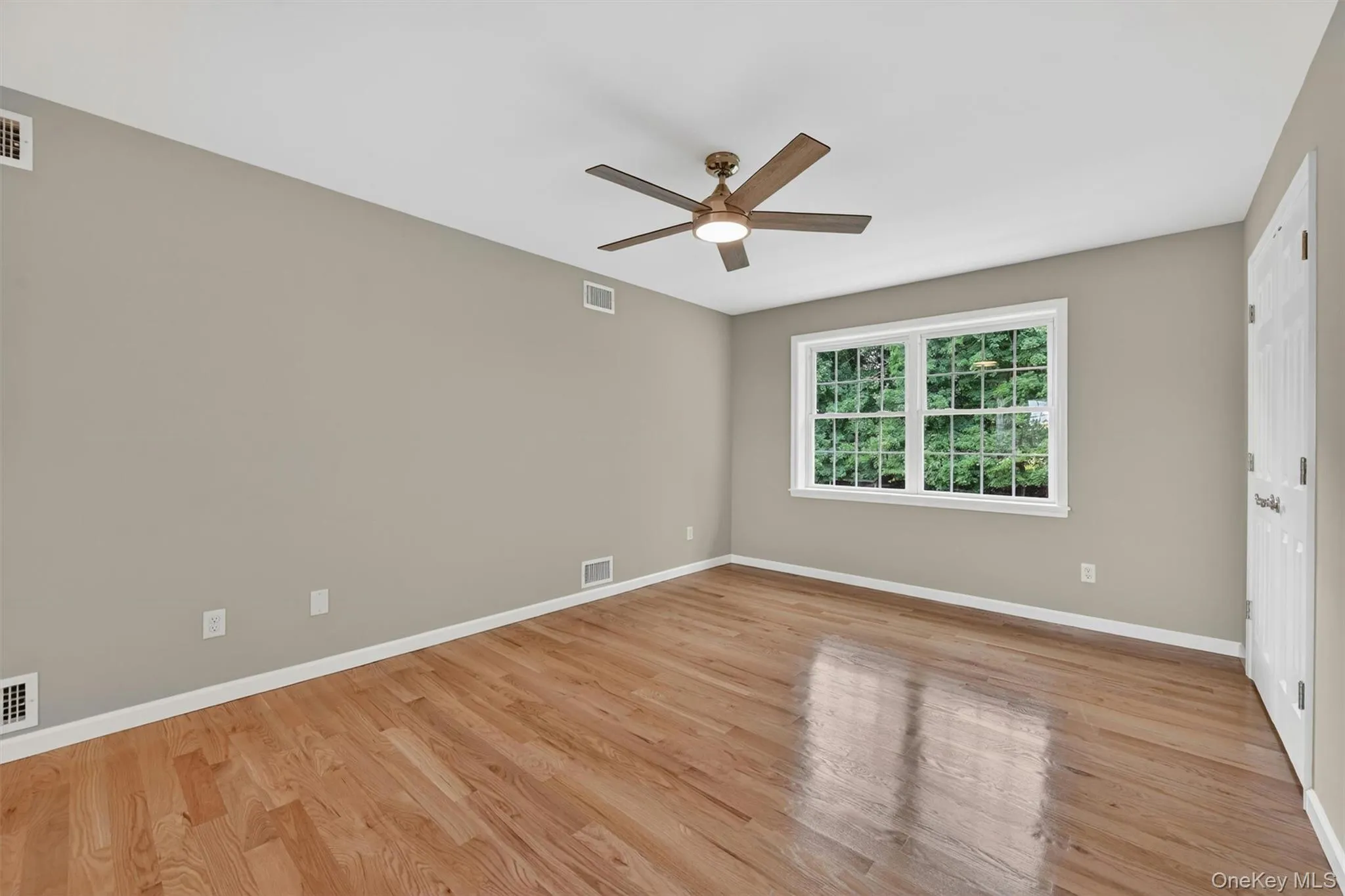 Spacious room featuring wood-finish flooring, a ceiling fan with integrated lighting, and recessed ceiling lights Spacious room featuring wood-finish flooring, a ceiling fan with integrated lighting, and recessed ceiling lights