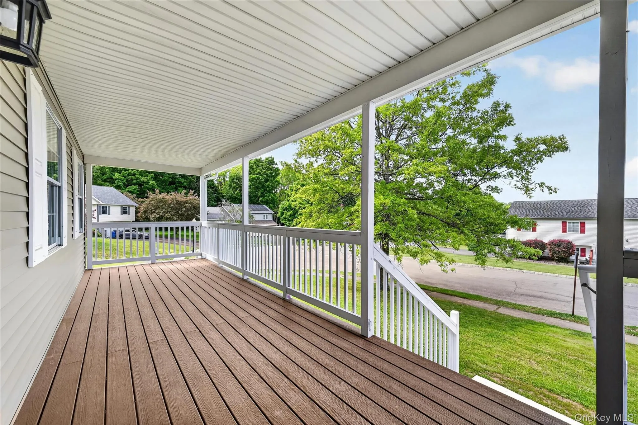 Covered porch featuring composite decking and white railings Covered porch featuring composite decking and white railings