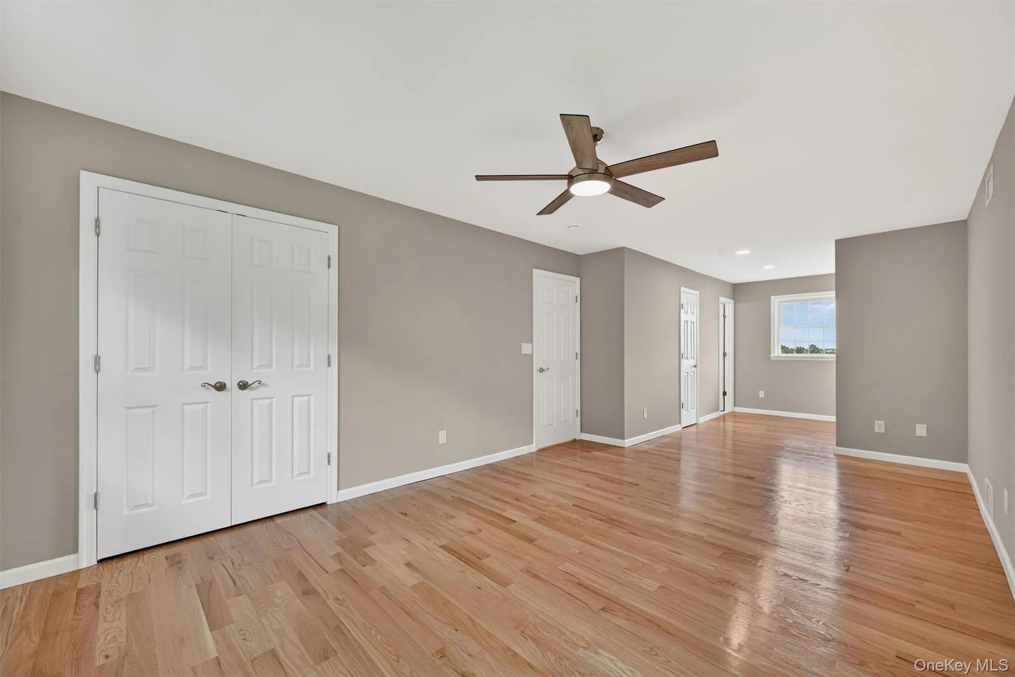 Spacious room featuring wood-finish flooring, a ceiling fan with integrated lighting, and recessed ceiling lights Spacious room featuring wood-finish flooring, a ceiling fan with integrated lighting, and recessed ceiling lights