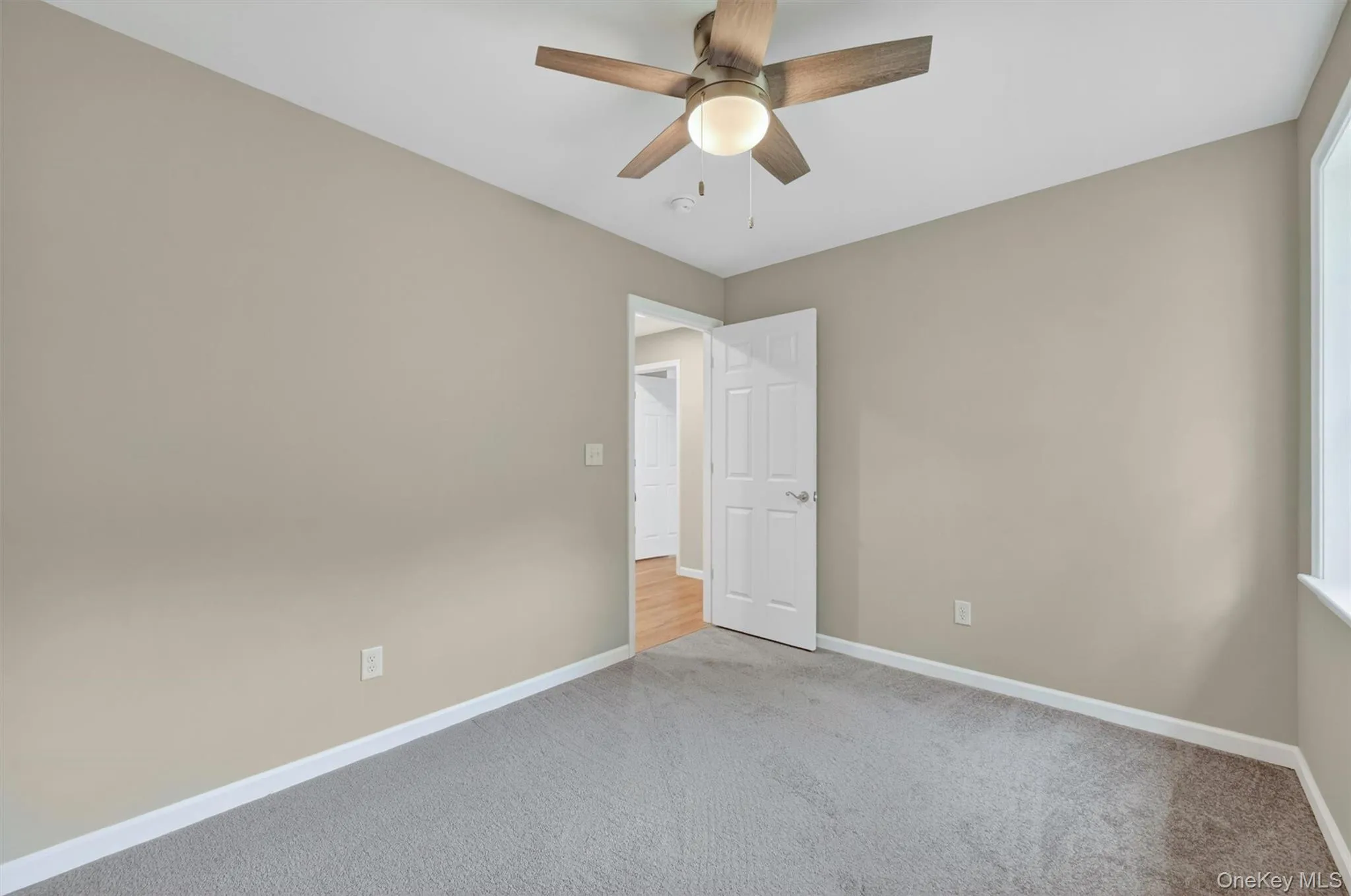Neutral tone walls with white trim, gray carpet flooring, and a ceiling fan with integrated lighting Neutral tone walls with white trim, gray carpet flooring, and a ceiling fan with integrated lighting