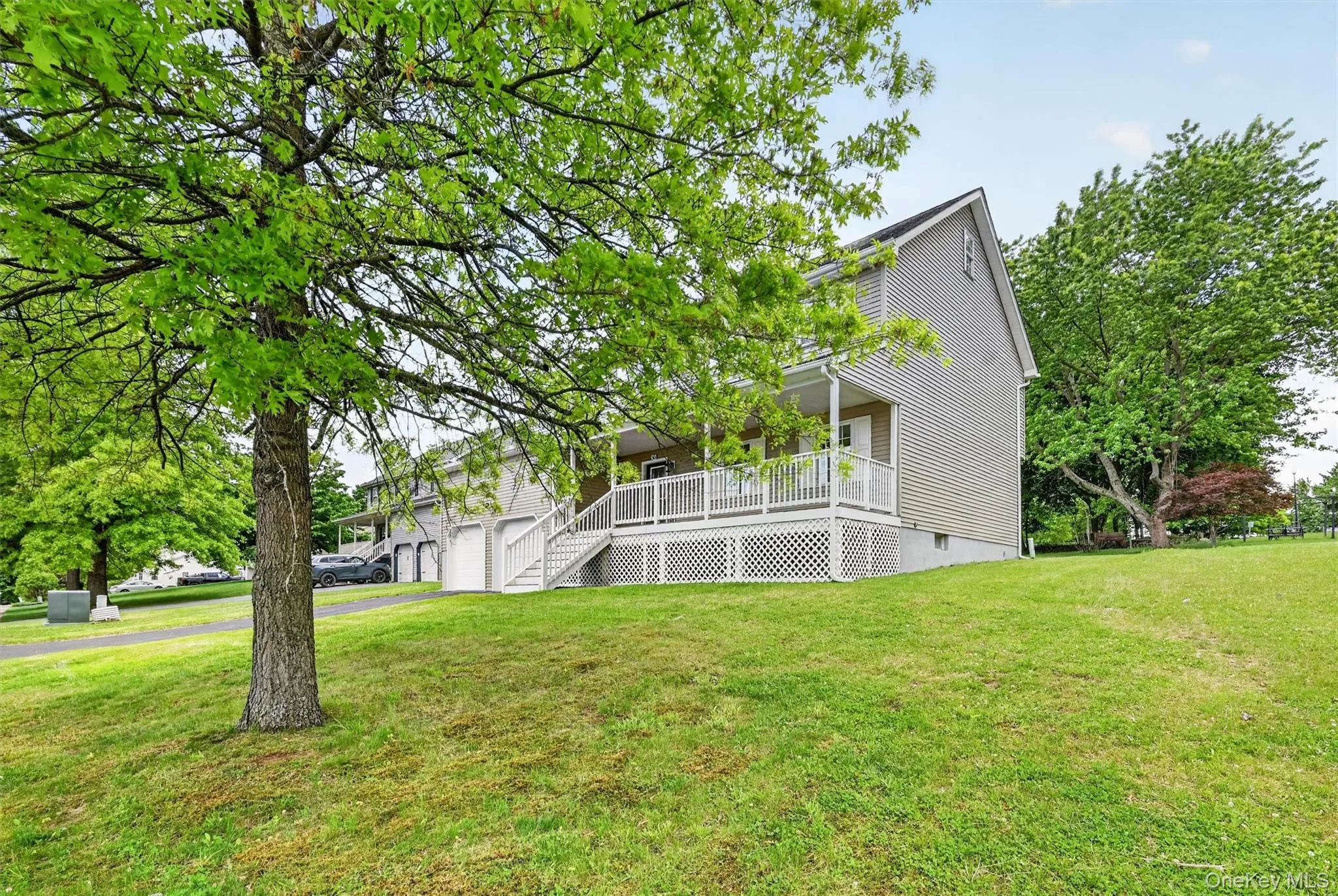 Exterior view featuring a neutral-toned siding, a covered front porch with white railings, and a foundational lattice Exterior view featuring a neutral-toned siding, a covered front porch with white railings, and a foundational lattice