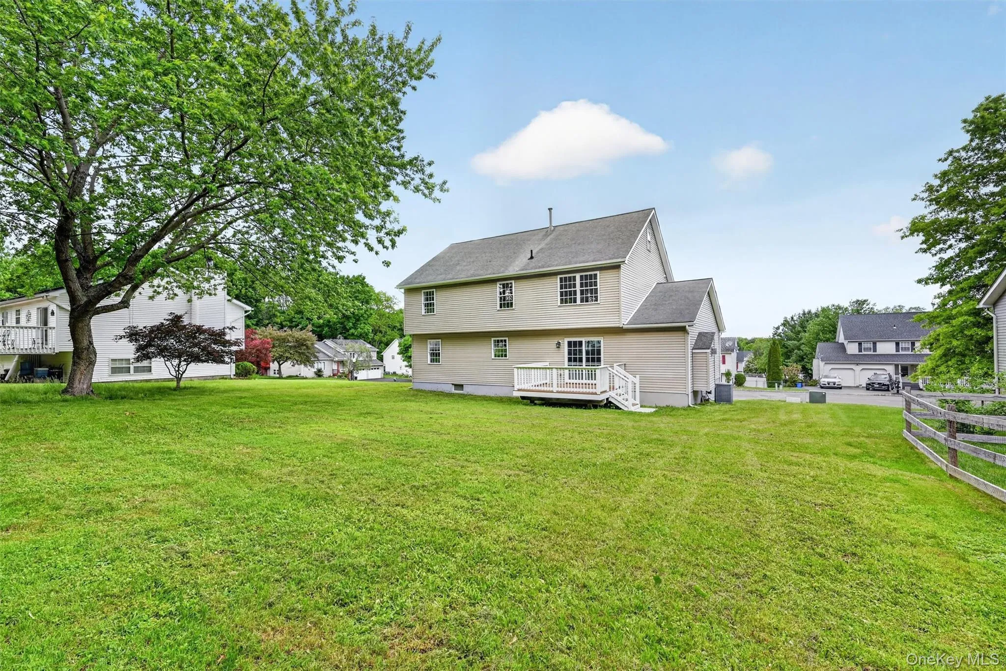 Expansive green lawn with a two-story residence featuring light-toned siding and multiple windows Expansive green lawn with a two-story residence featuring light-toned siding and multiple windows