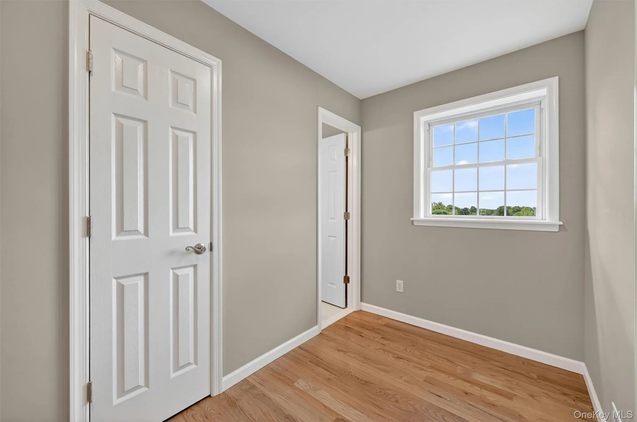 Room featuring wood-finish flooring, neutral wall paint, and white trim Room featuring wood-finish flooring, neutral wall paint, and white trim