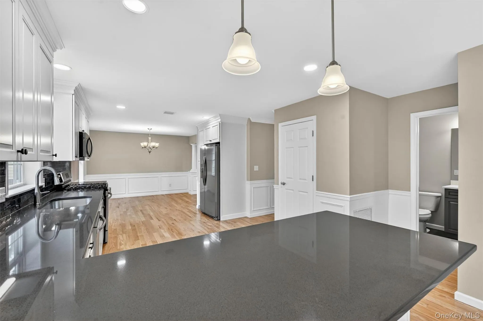 Kitchen featuring dark countertops, white cabinetry, stainless steel refrigerator, and recessed lighting Kitchen featuring dark countertops, white cabinetry, stainless steel refrigerator, and recessed lighting