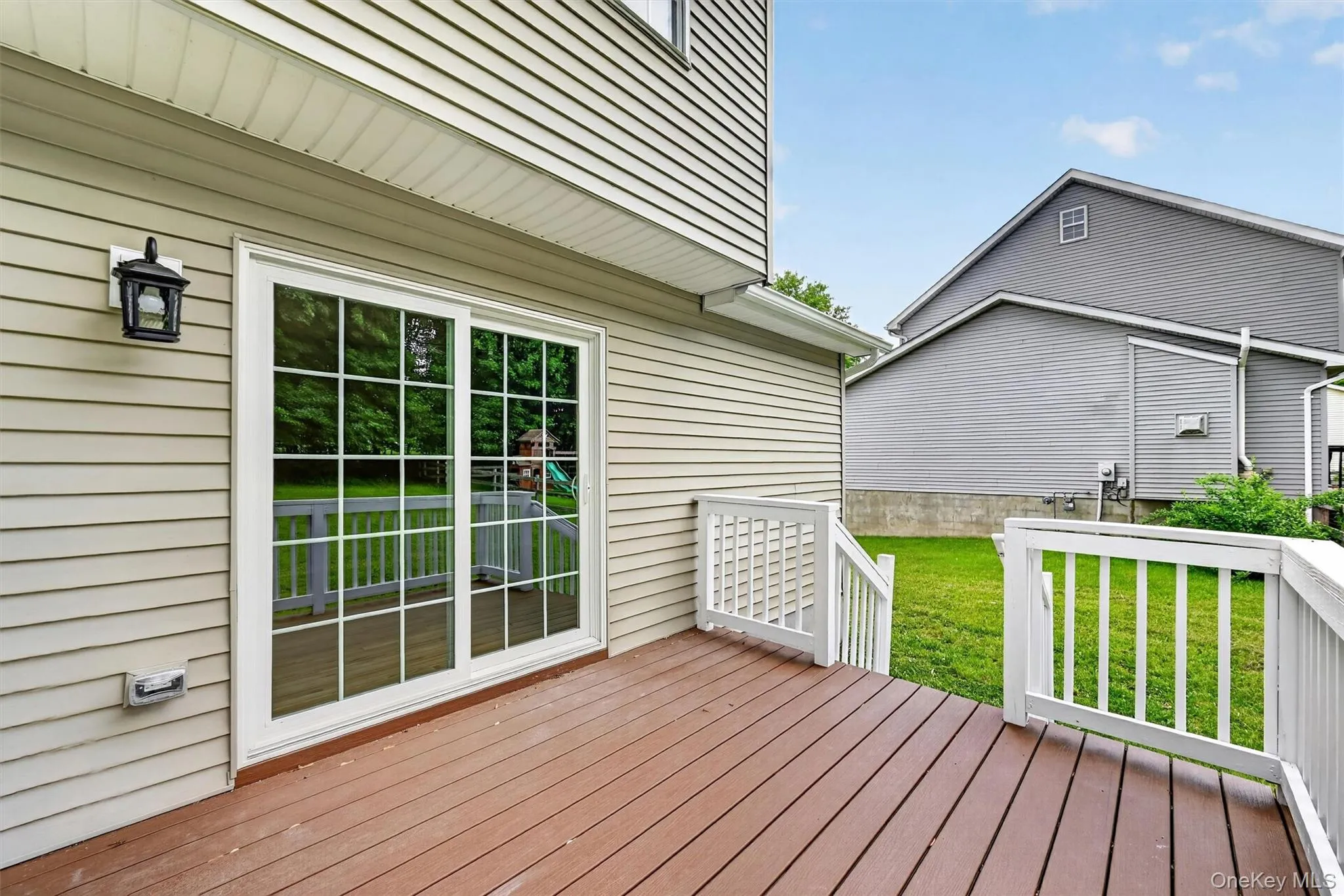Back deck featuring wood-finish flooring, white railing, and a sliding glass door with grid panes Back deck featuring wood-finish flooring, white railing, and a sliding glass door with grid panes