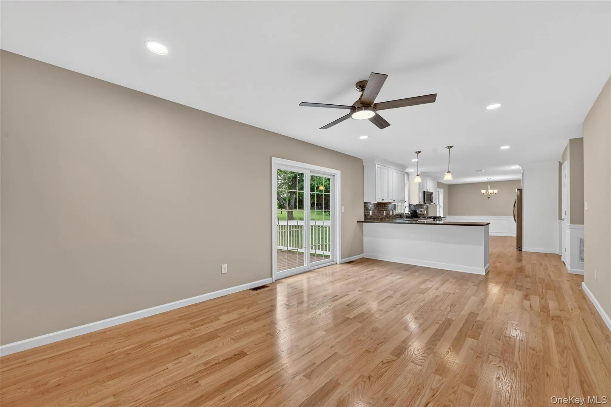 Spacious open-concept living area featuring wood-finish flooring, recessed lighting, and a ceiling fan Spacious open-concept living area featuring wood-finish flooring, recessed lighting, and a ceiling fan