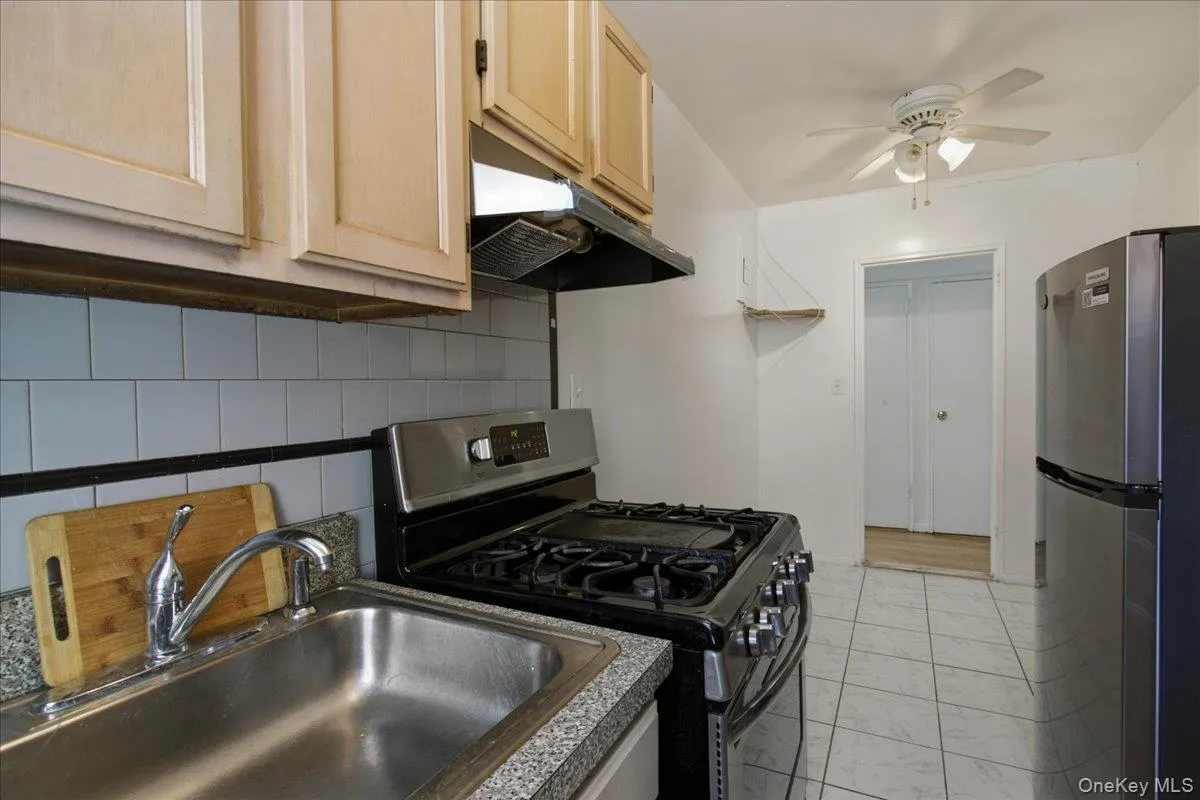 closer view of new stainless fridge and rangehood with coordinating black 5-burner gas range w griddle closer view of new stainless fridge and rangehood with coordinating black 5-burner gas range w griddle
