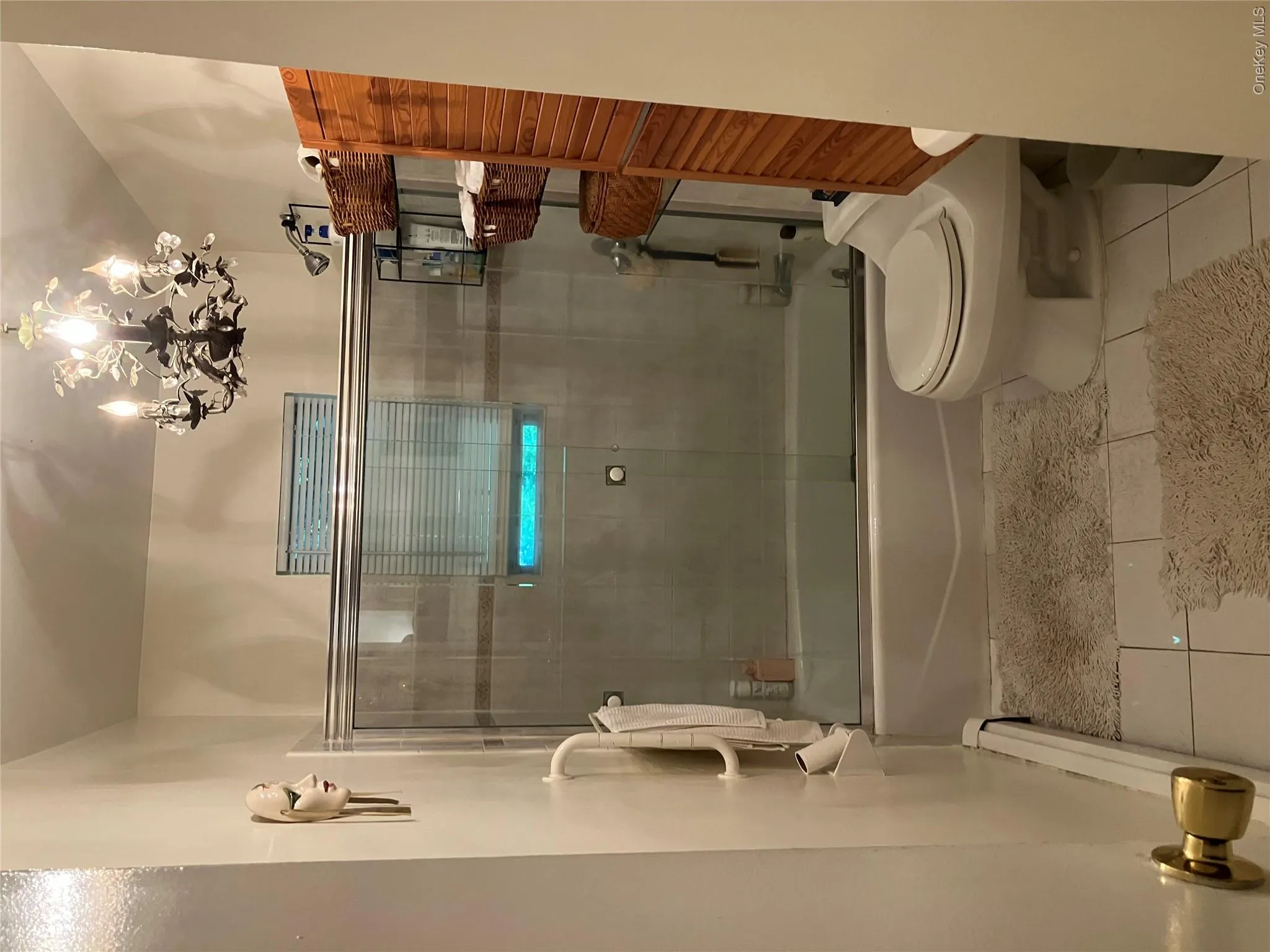 Bathroom featuring a full tub with sliding glass doors, tiled flooring, and a decorative ceiling light fixture Bathroom featuring a full tub with sliding glass doors, tiled flooring, and a decorative ceiling light fixture