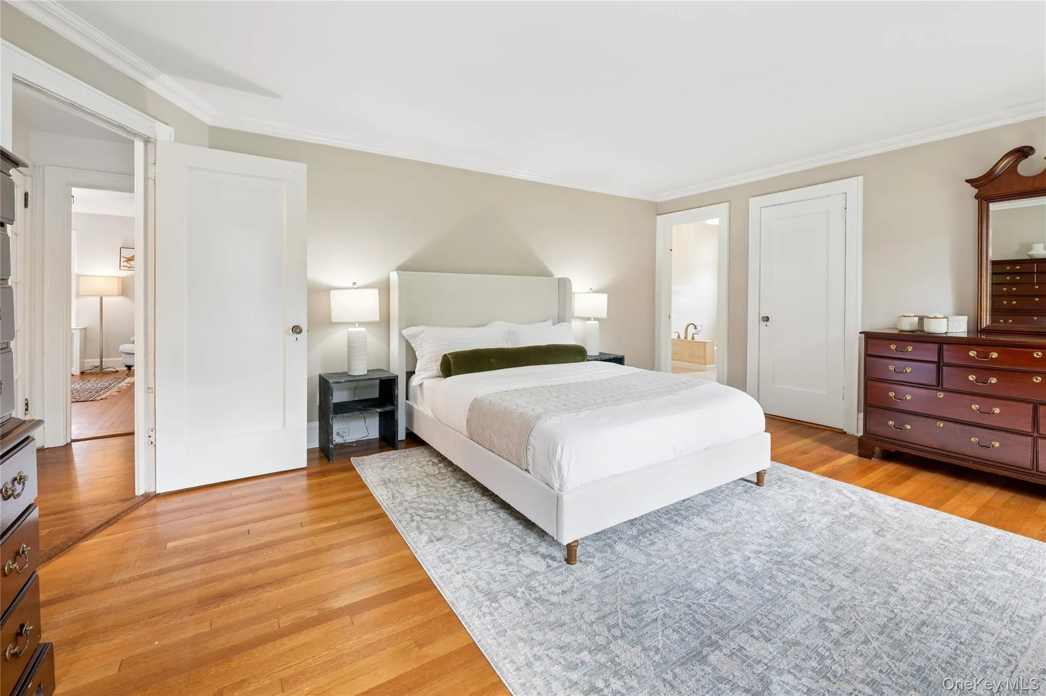 Spacious room with hardwood flooring, light-toned walls, and white crown molding Spacious room with hardwood flooring, light-toned walls, and white crown molding