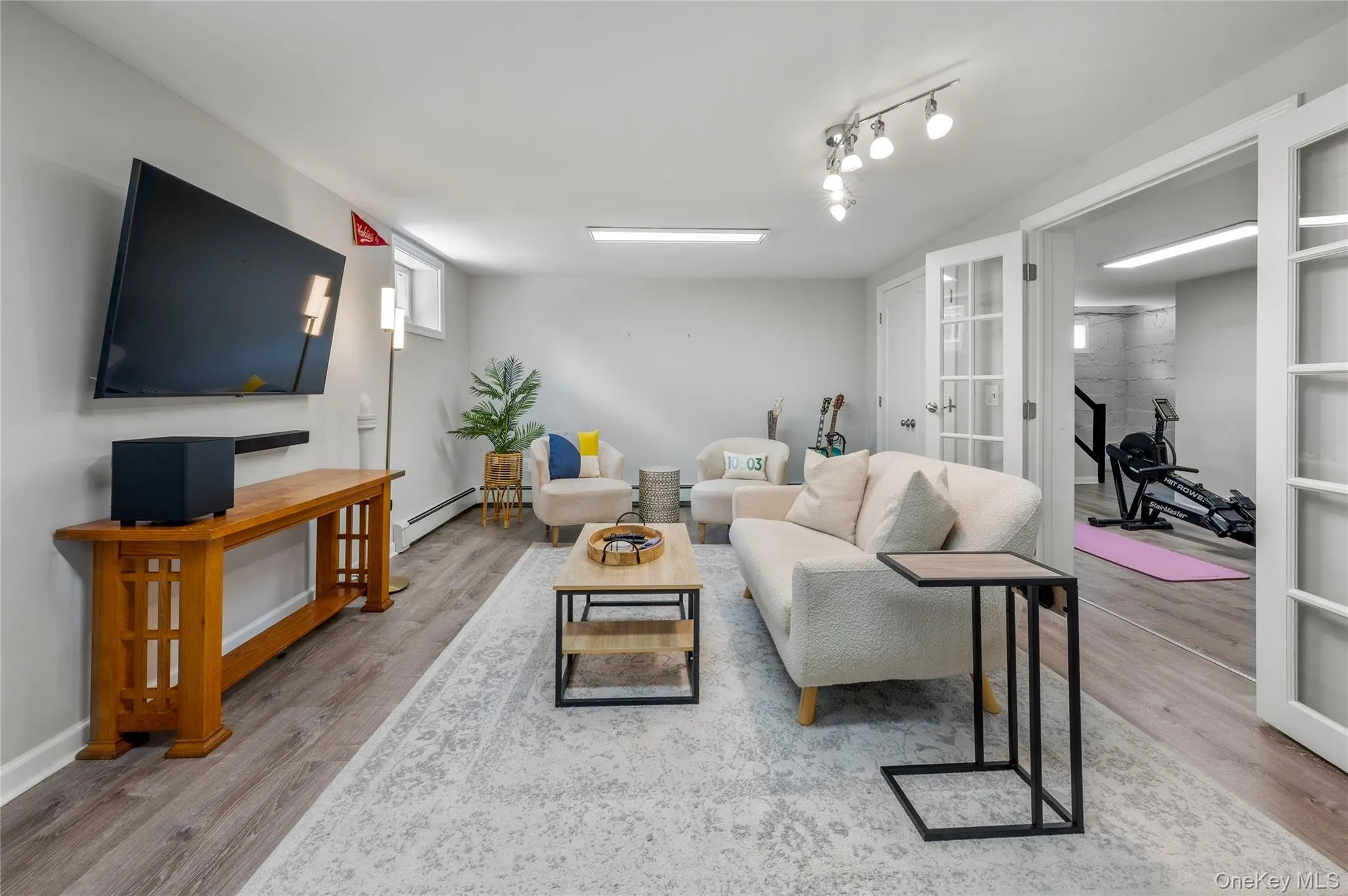 Spacious recreation room featuring wood-finish flooring and light gray walls connects to garage Spacious recreation room featuring wood-finish flooring and light gray walls connects to garage