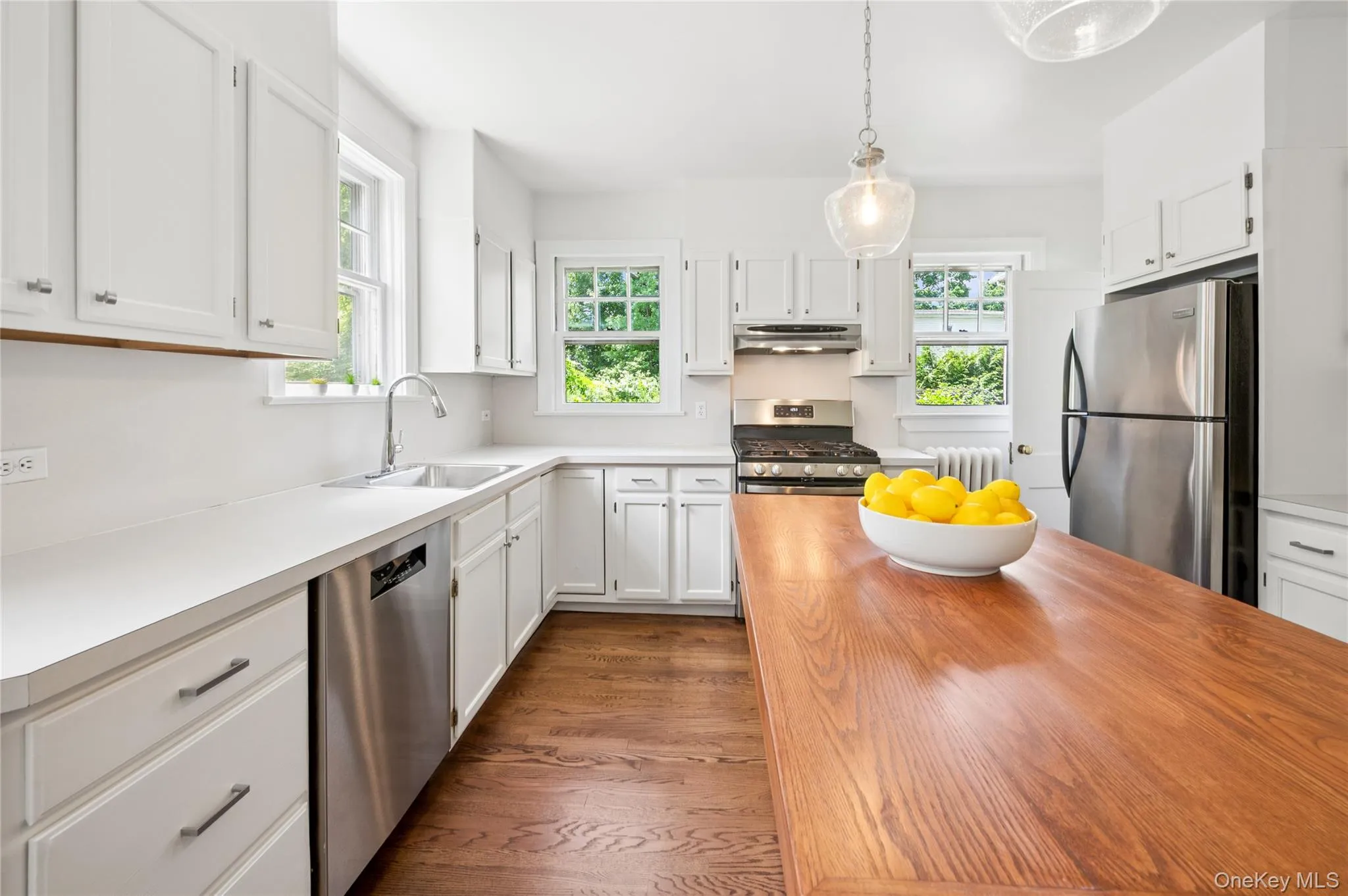 Kitchen featuring a wood-finish island, white cabinetry, stainless steel appliances, and wood-finish flooring Kitchen featuring a wood-finish island, white cabinetry, stainless steel appliances, and wood-finish flooring
