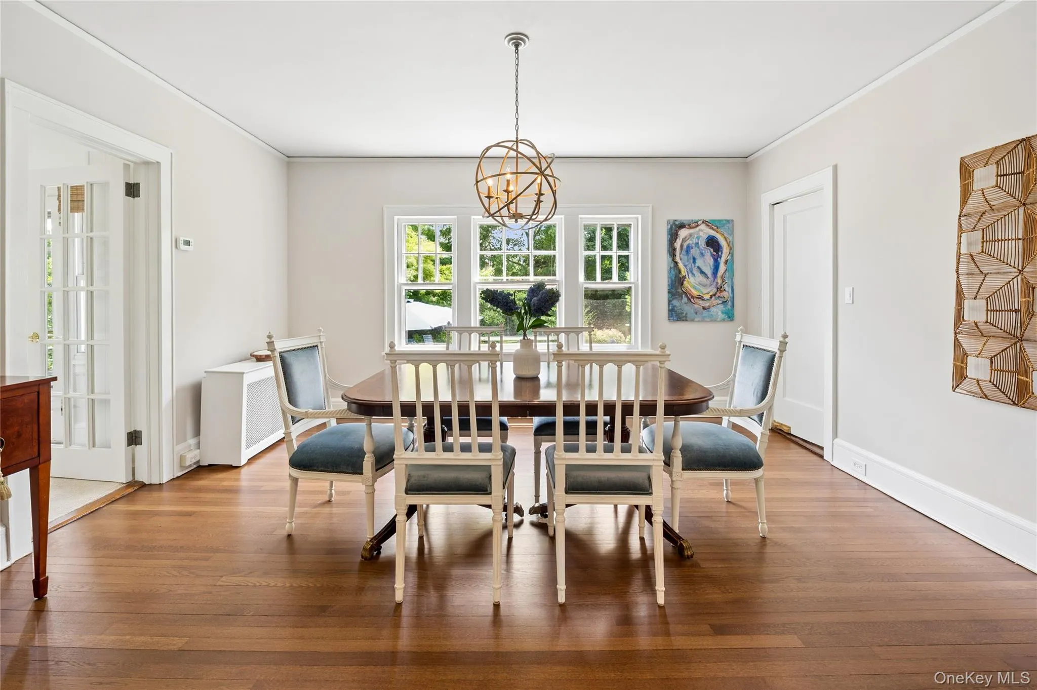 Hardwood flooring throughout a dining space featuring a chandelier, three windows, and a French door Hardwood flooring throughout a dining space featuring a chandelier, three windows, and a French door