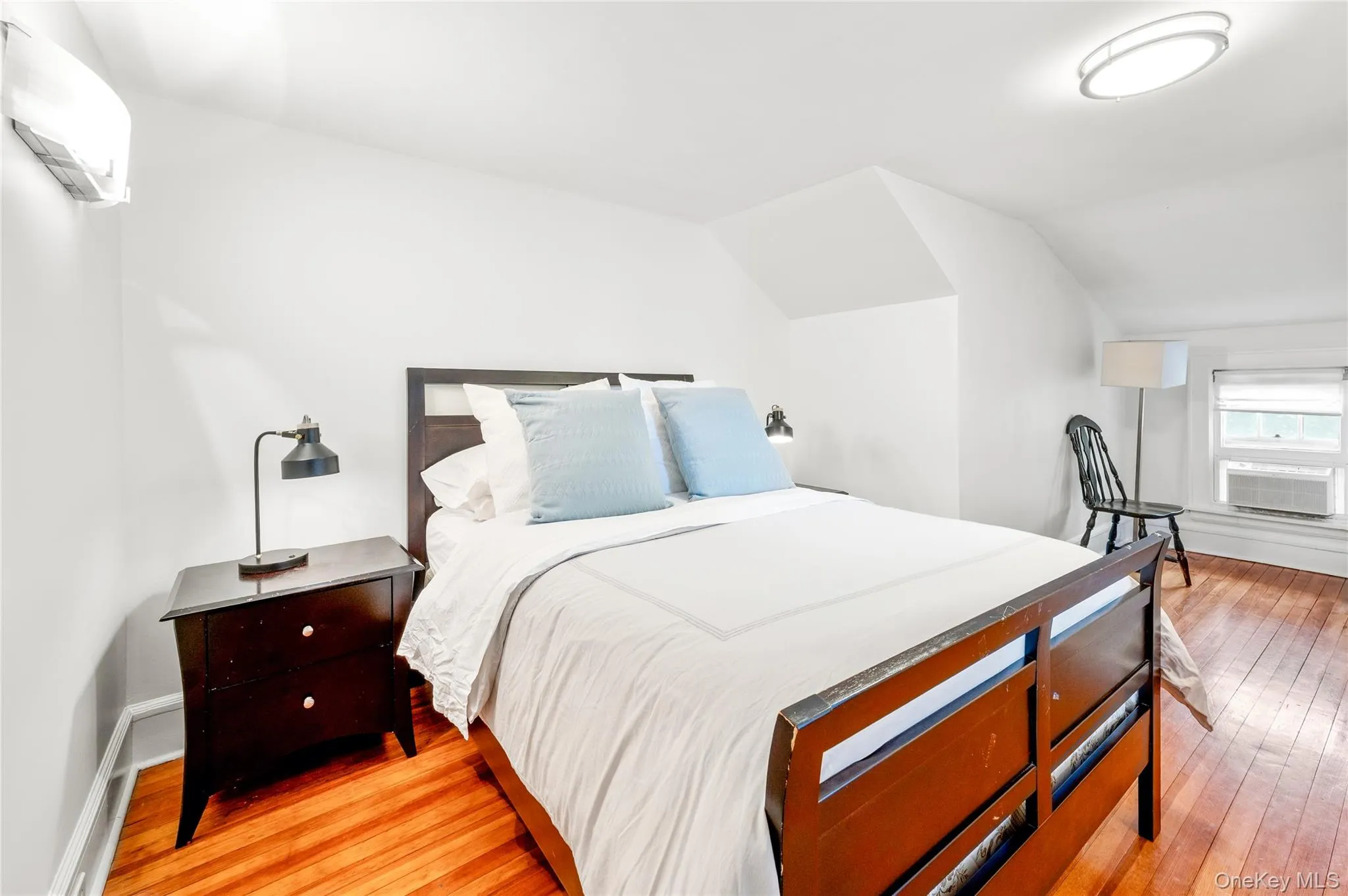 Bedroom featuring warm hardwood flooring and bright white walls Bedroom featuring warm hardwood flooring and bright white walls