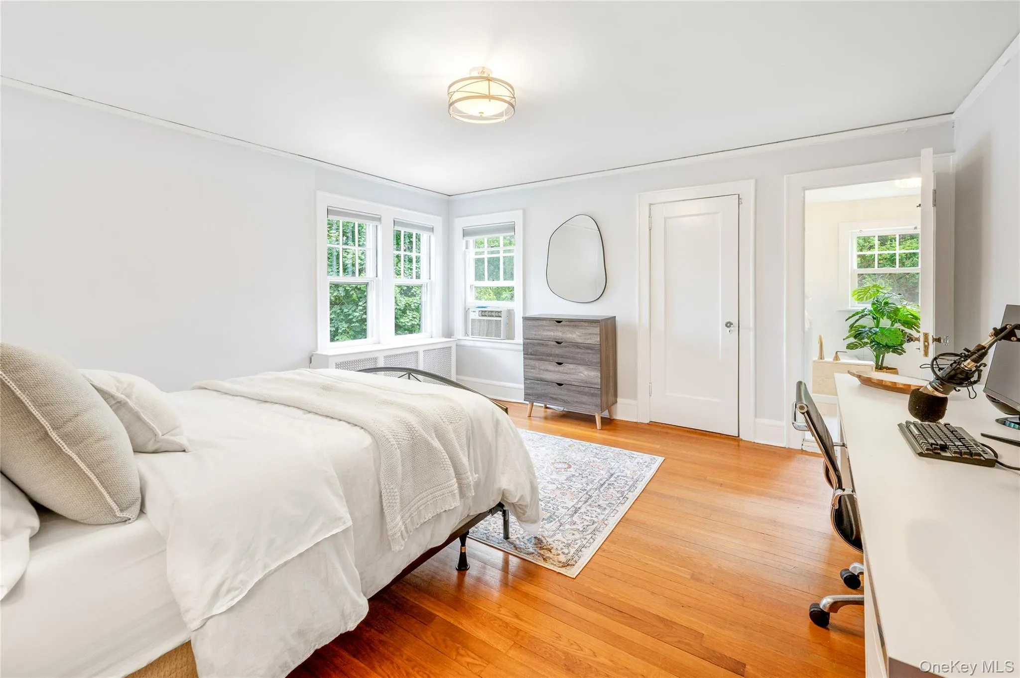Bedroom featuring hardwood flooring, white walls, and a multi-pane window with a deep sill Bedroom featuring hardwood flooring, white walls, and a multi-pane window with a deep sill