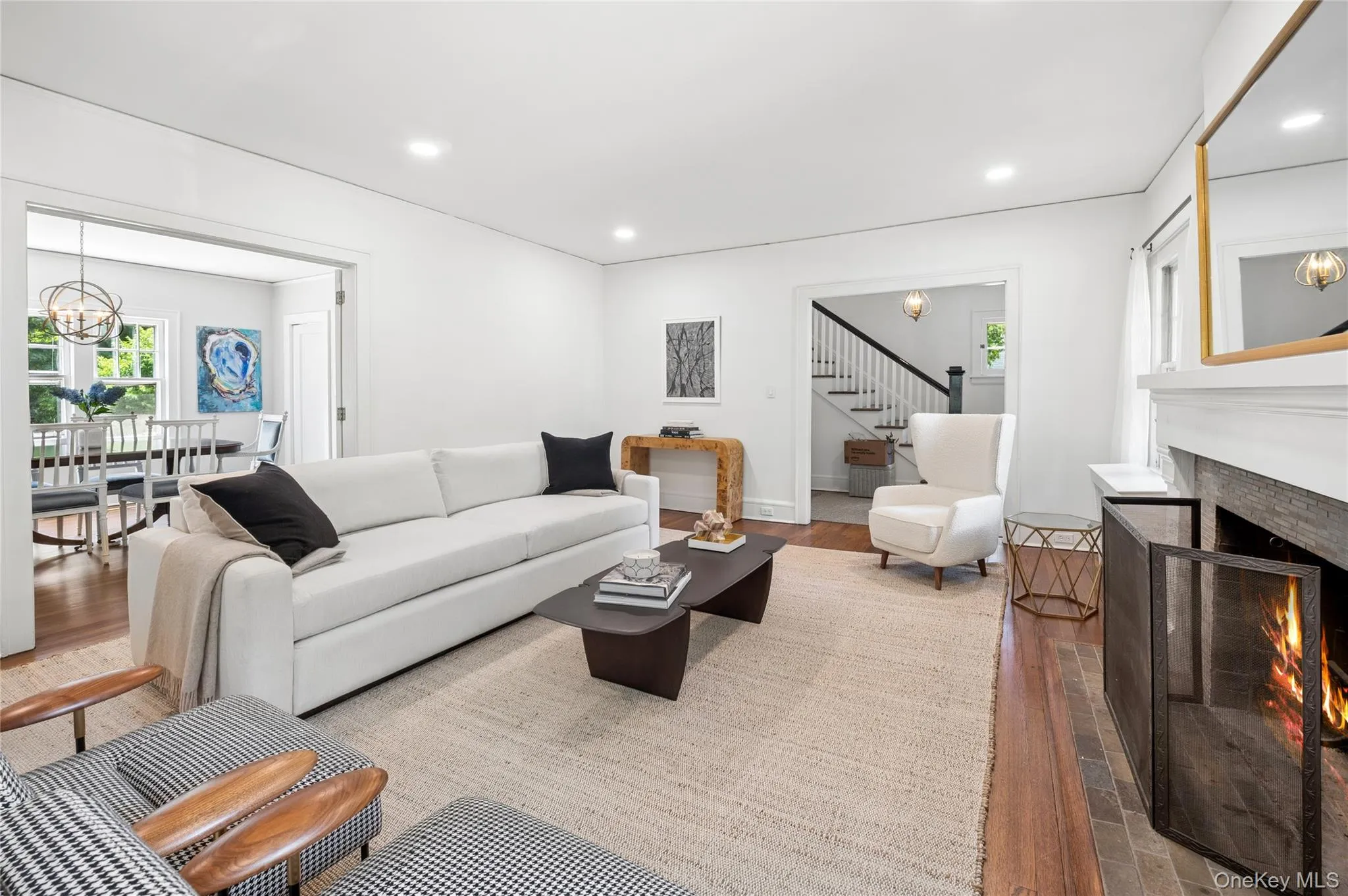 Living room featuring a fireplace with a stone surround, hardwood flooring, and recessed lighting Living room featuring a fireplace with a stone surround, hardwood flooring, and recessed lighting
