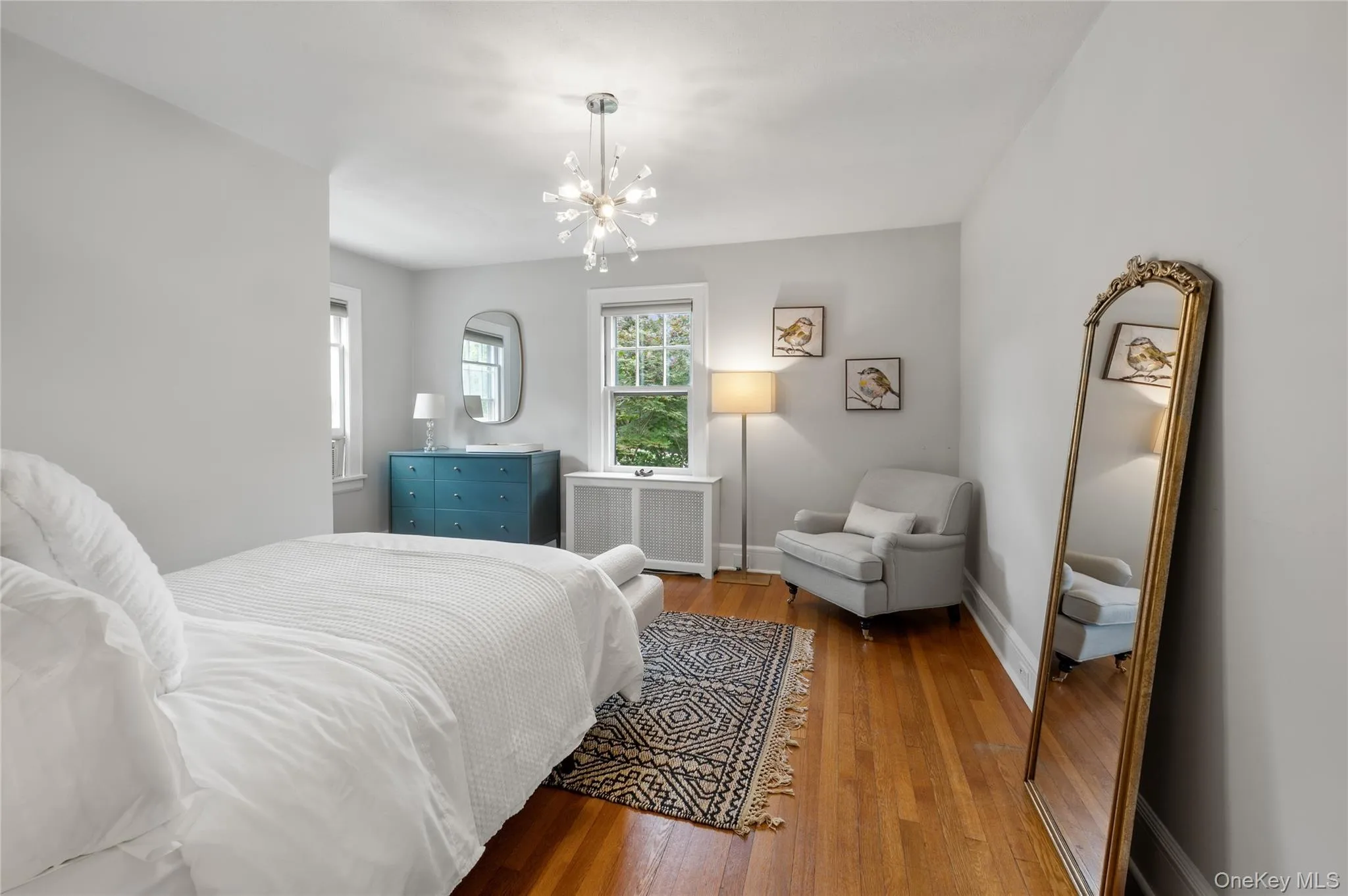 Hardwood flooring extends throughout this room, featuring a contemporary chandelier Hardwood flooring extends throughout this room, featuring a contemporary chandelier