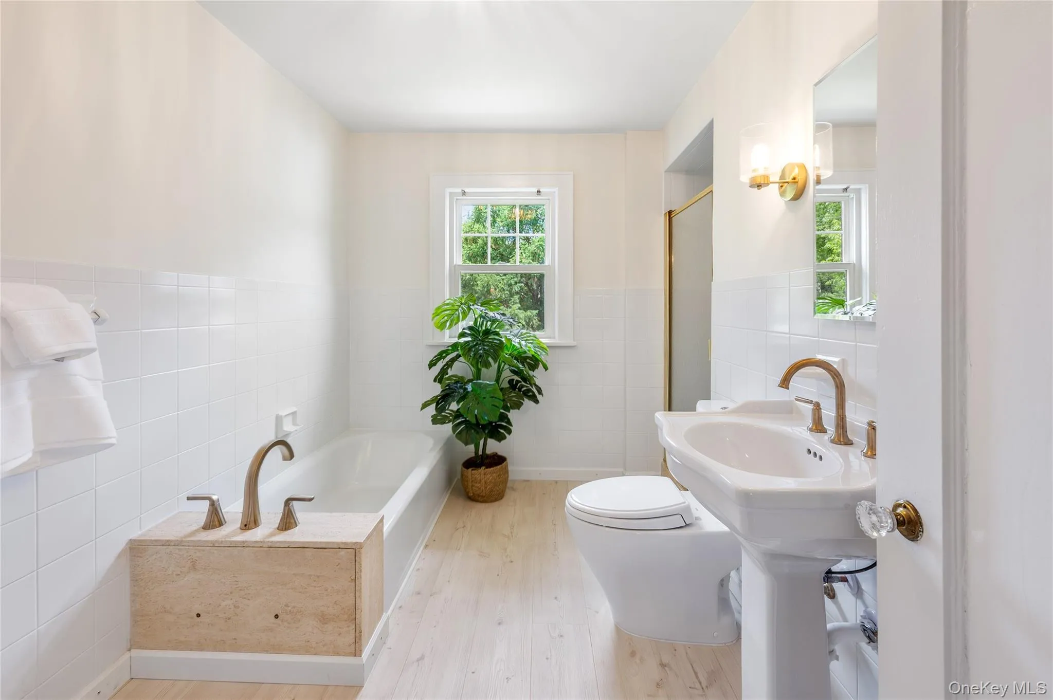 Bathroom featuring light wood finish flooring and white tiled walls Bathroom featuring light wood finish flooring and white tiled walls