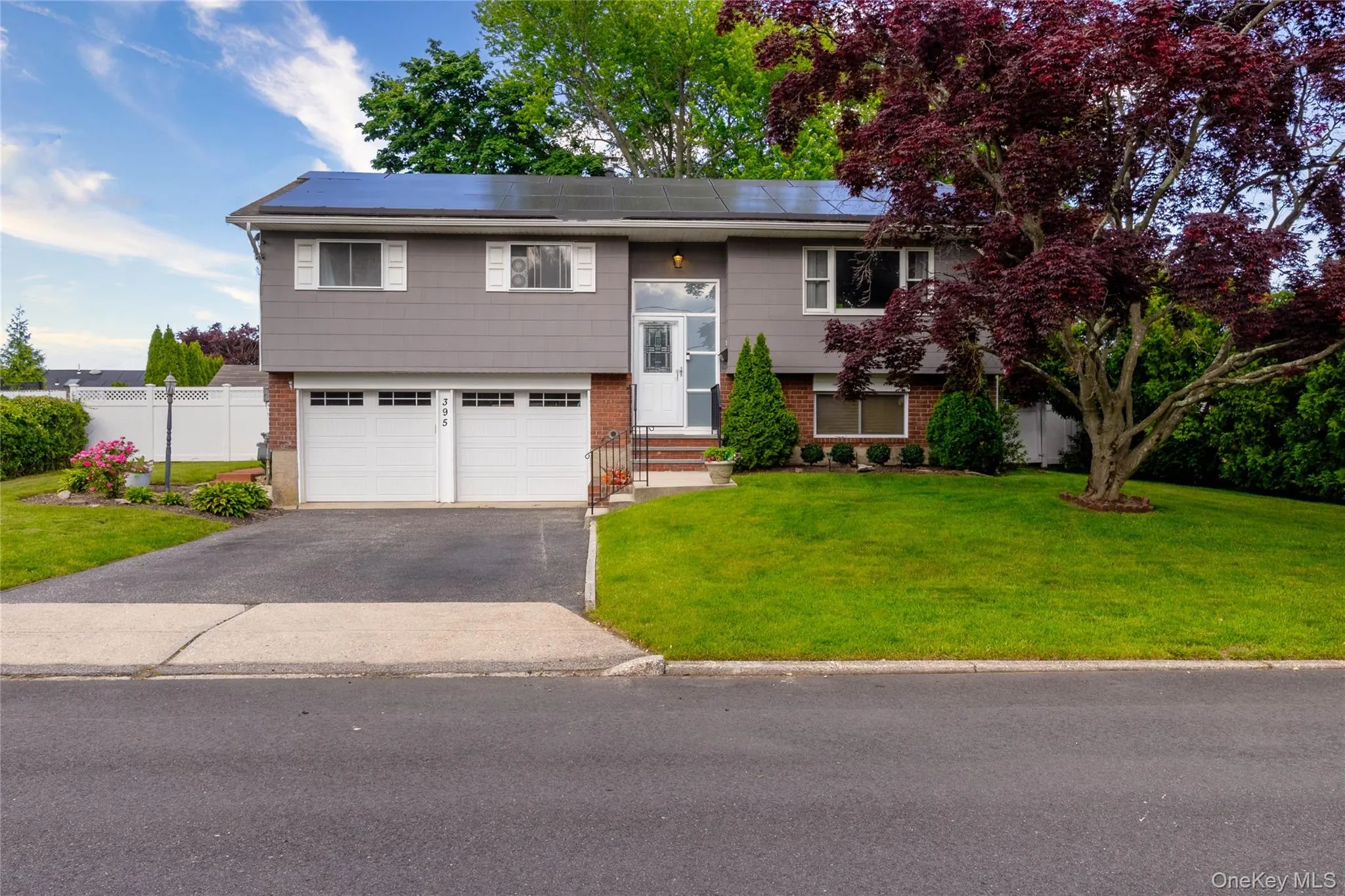 Split-level residence featuring gray siding, a brick facade, and a two-car garage Split-level residence featuring gray siding, a brick facade, and a two-car garage