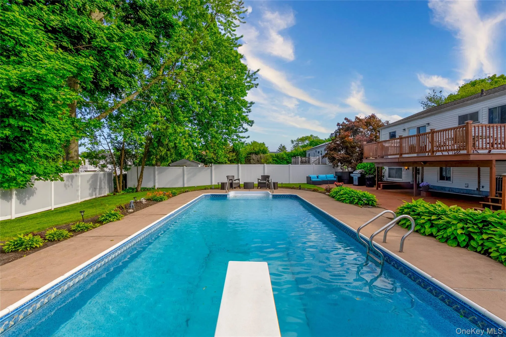 Rectangular in-ground swimming pool featuring a diving board and entry steps Rectangular in-ground swimming pool featuring a diving board and entry steps