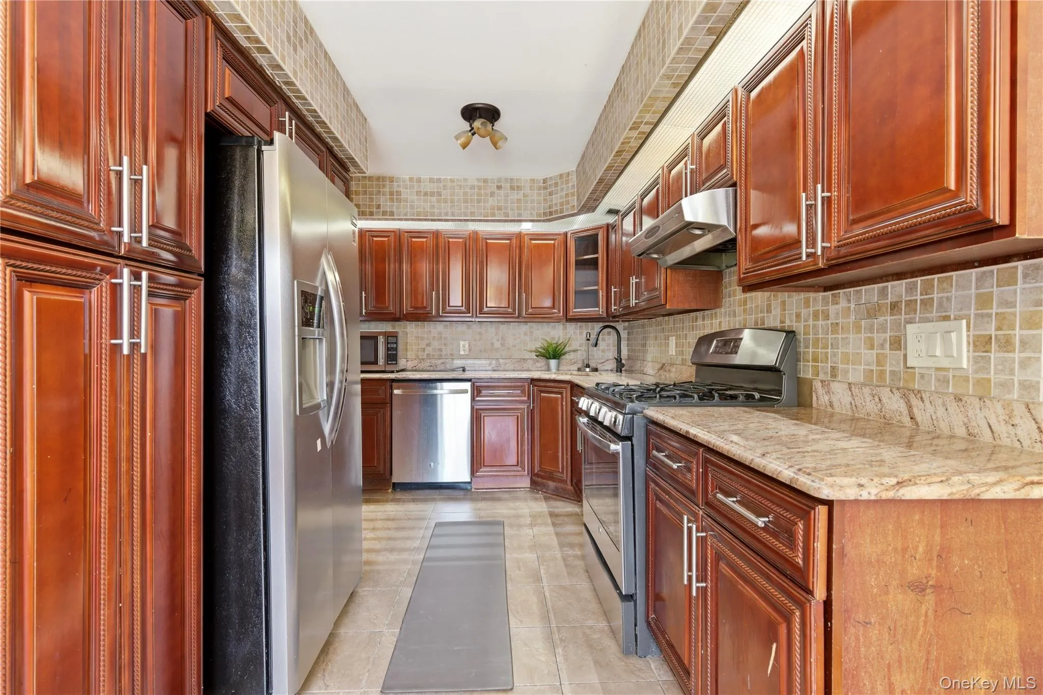 Galley kitchen with cherry wood-finish cabinetry and stainless steel appliances Galley kitchen with cherry wood-finish cabinetry and stainless steel appliances