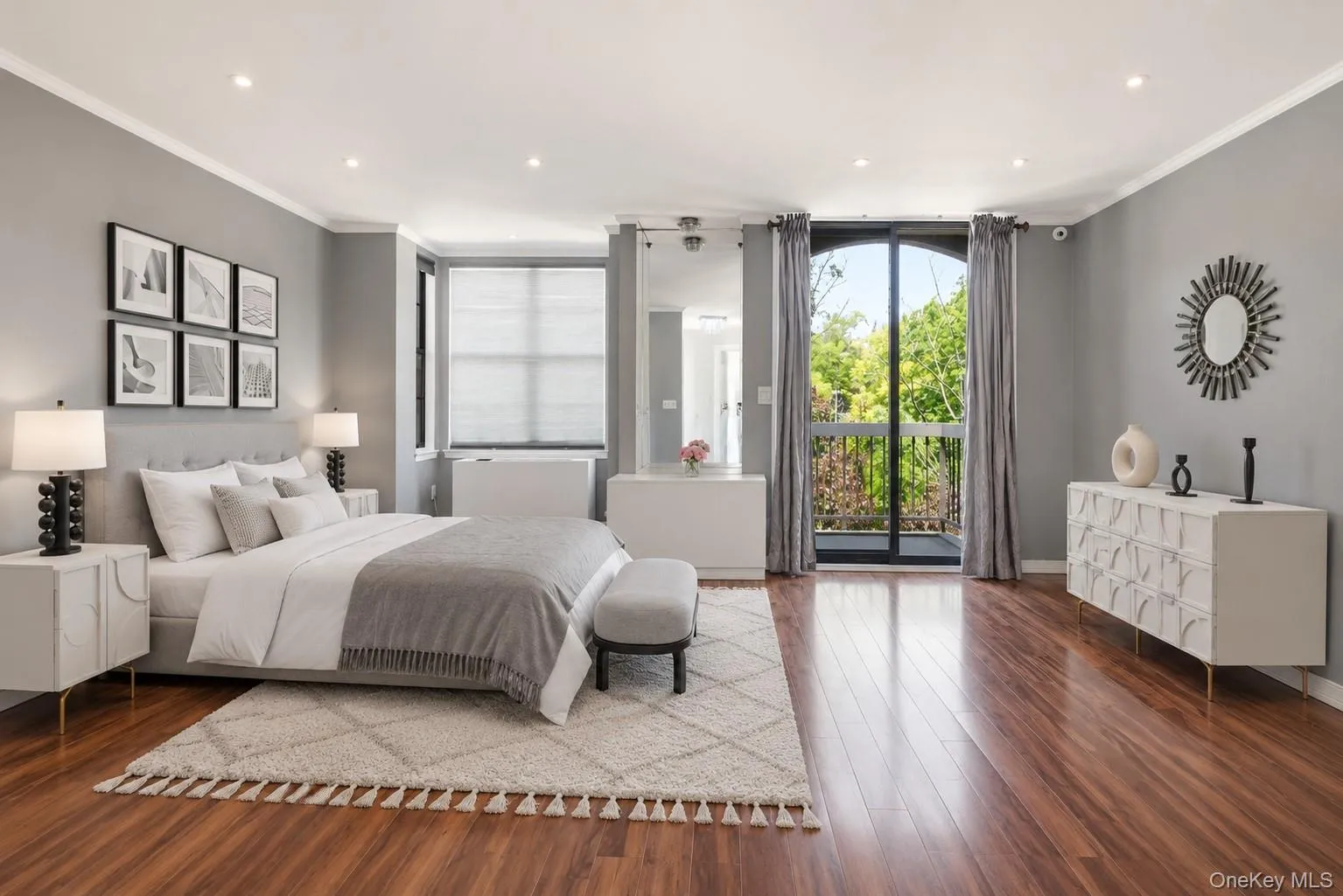 Expansive room featuring rich wood-finish flooring, recessed lighting, and a large arched glass door opening to a balcony Expansive room featuring rich wood-finish flooring, recessed lighting, and a large arched glass door opening to a balcony