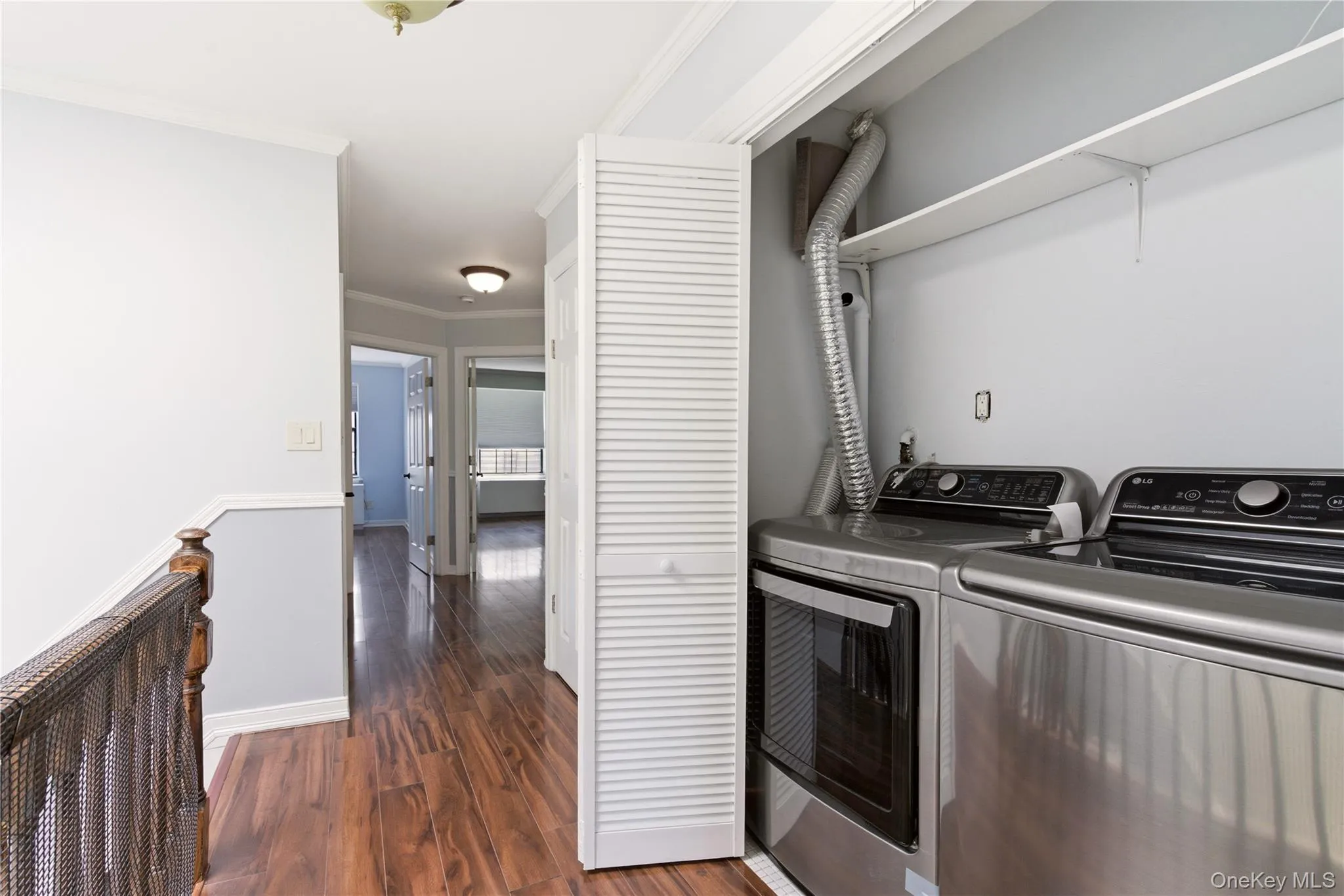 Convenient laundry area featuring bi-fold louvered doors and overhead shelving Convenient laundry area featuring bi-fold louvered doors and overhead shelving