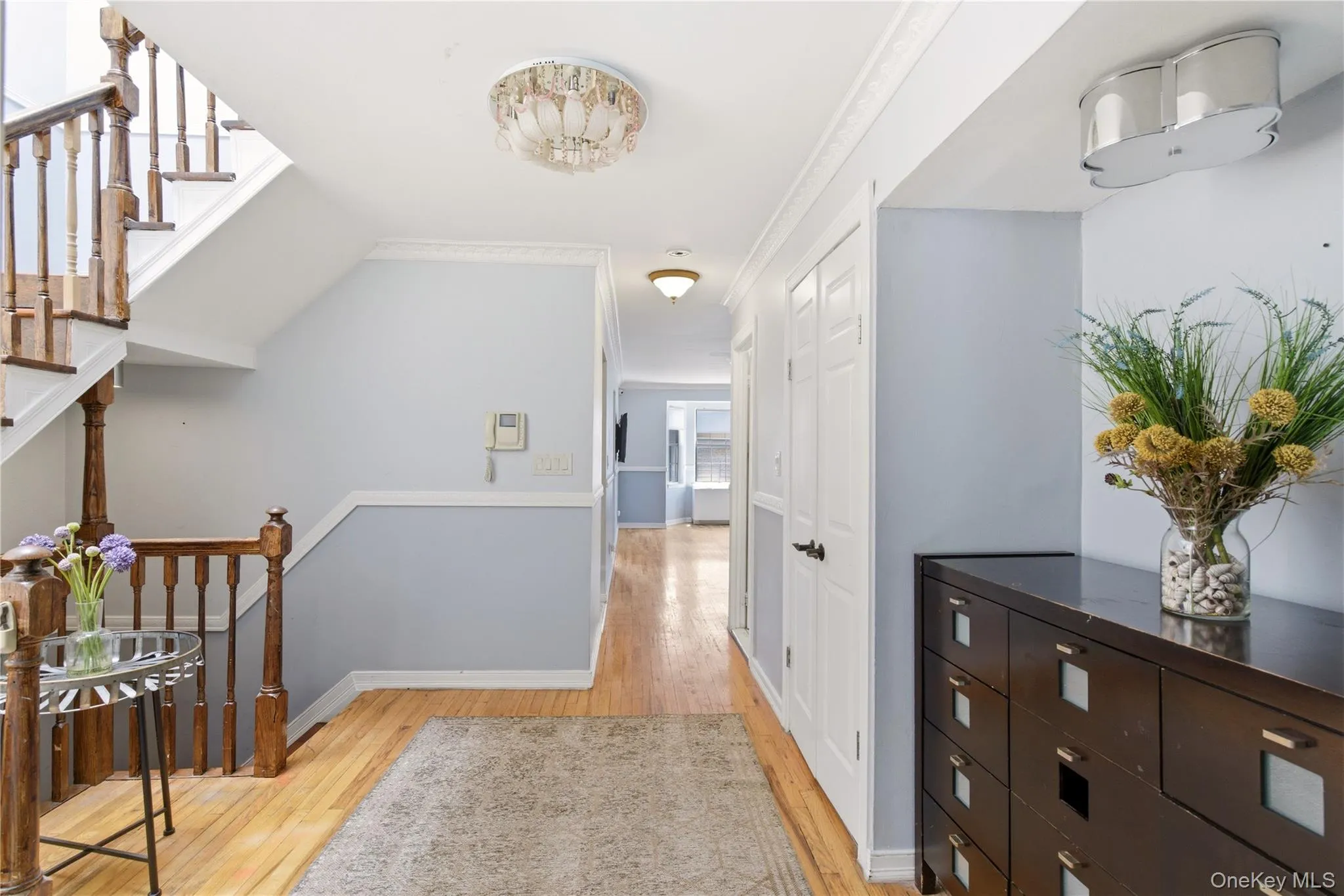 Inviting entryway featuring hardwood flooring, a detailed wooden staircase, and built-in closet storage Inviting entryway featuring hardwood flooring, a detailed wooden staircase, and built-in closet storage