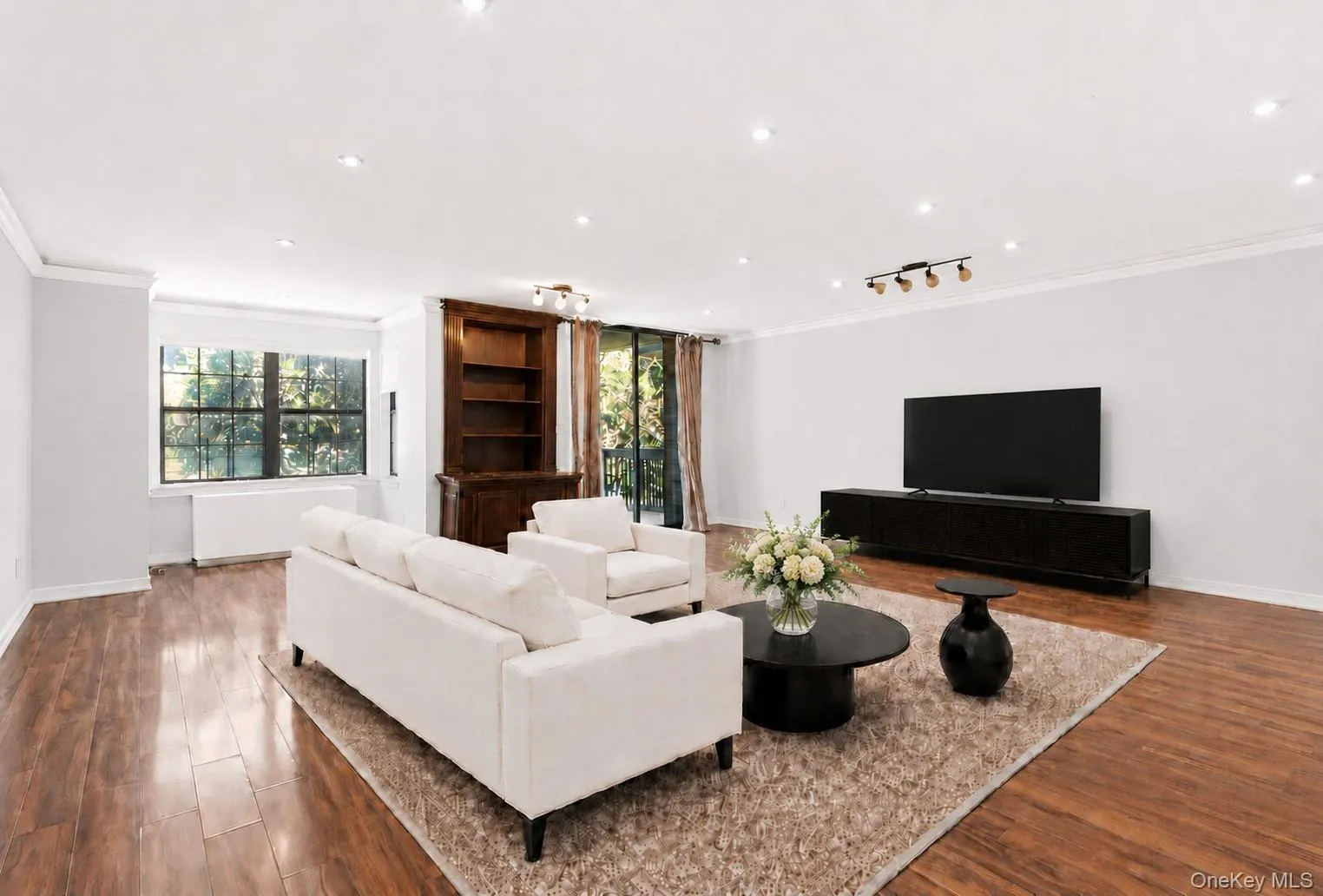 Spacious living area featuring wood-finish flooring, recessed lighting, and crown molding Spacious living area featuring wood-finish flooring, recessed lighting, and crown molding