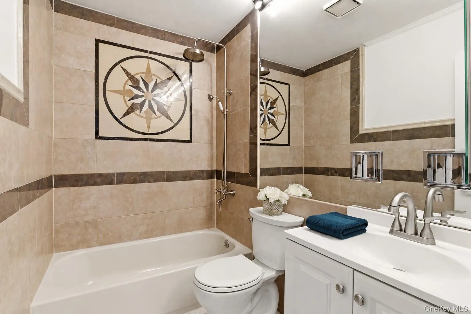 Full bathroom featuring a tiled shower and bath combination with a decorative compass rose accent Full bathroom featuring a tiled shower and bath combination with a decorative compass rose accent