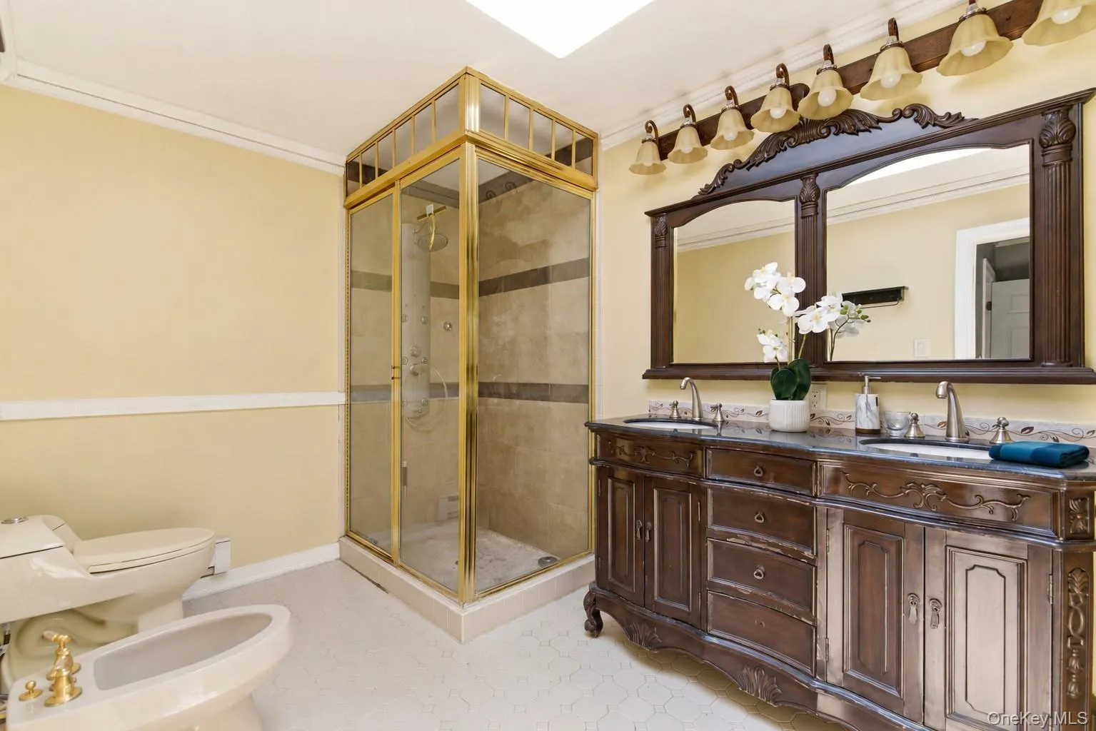 Double vanity with ornate wood cabinetry, dual undermount sinks, and a stone-finish countertop Double vanity with ornate wood cabinetry, dual undermount sinks, and a stone-finish countertop