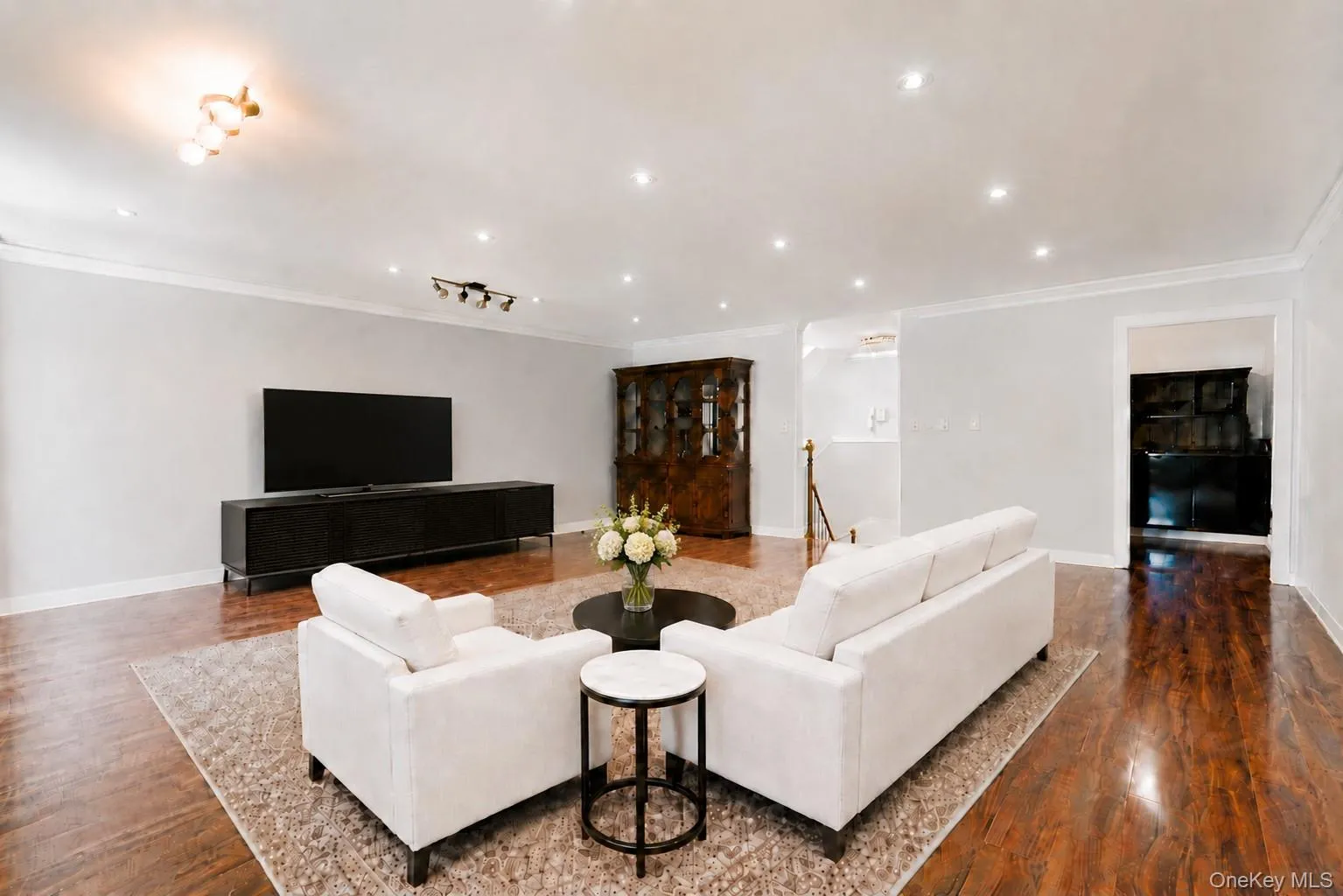 Living area featuring rich wood-finish flooring, recessed lighting, crown molding, and a built-in display cabinet Living area featuring rich wood-finish flooring, recessed lighting, crown molding, and a built-in display cabinet