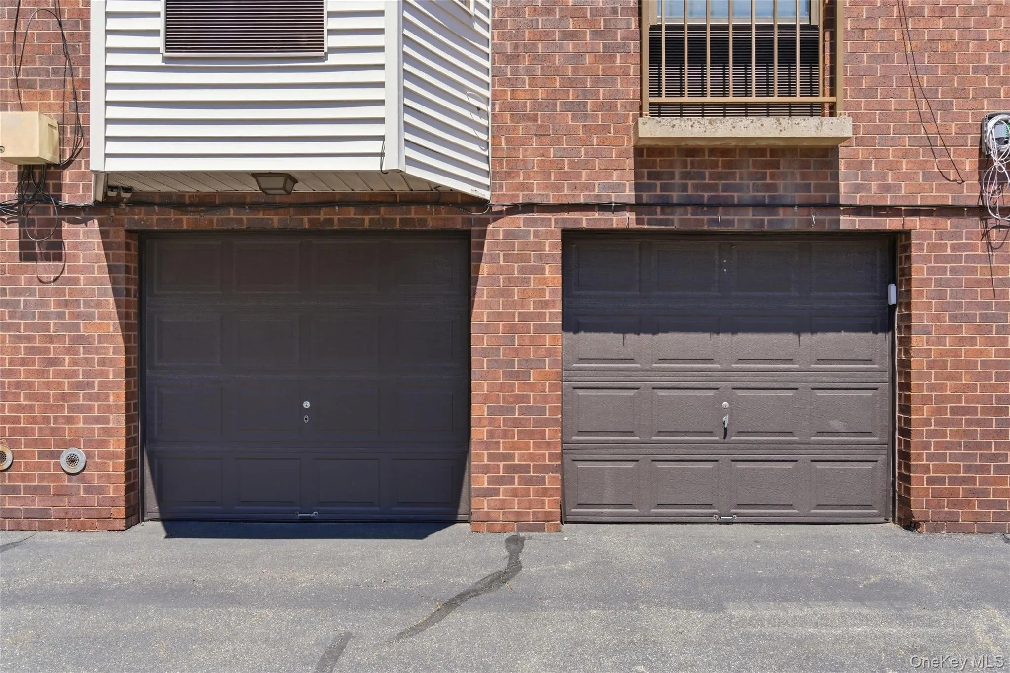 Two garage doors set within a brick facade, featuring paneled designs Two garage doors set within a brick facade, featuring paneled designs