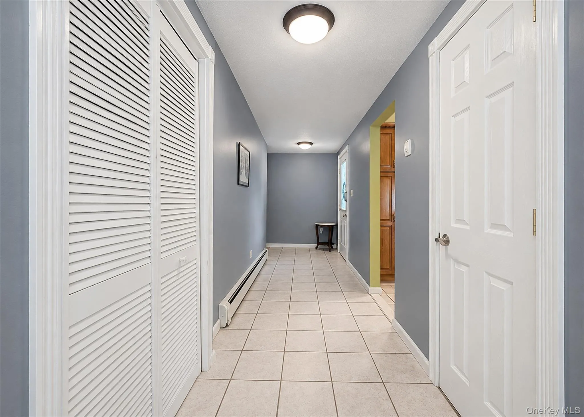 Hallway featuring neutral tile flooring and gray wall paint Hallway featuring neutral tile flooring and gray wall paint