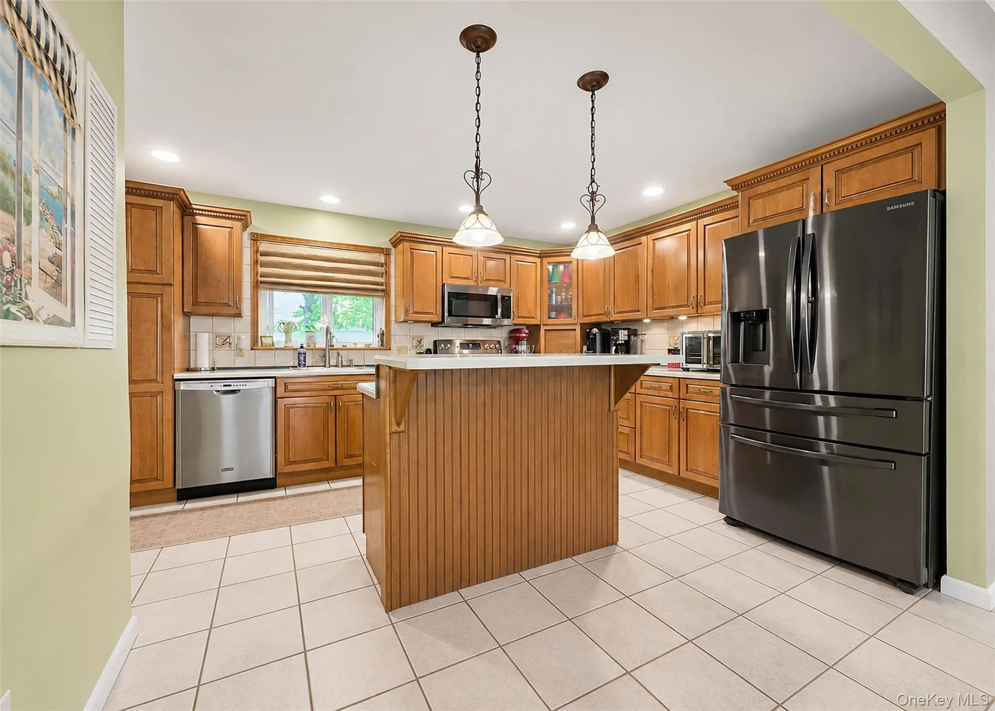 Kitchen featuring warm wood cabinetry, a central island with a breakfast bar, and stainless steel appliances Kitchen featuring warm wood cabinetry, a central island with a breakfast bar, and stainless steel appliances