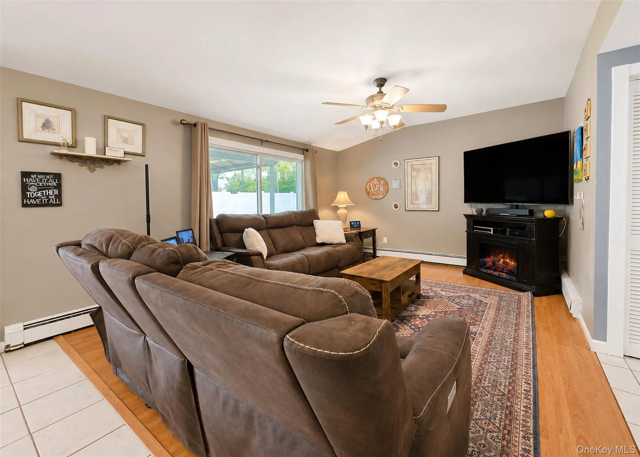 Living area featuring wood-finish flooring, a ceiling fan with integrated lighting, and a large sliding glass door Living area featuring wood-finish flooring, a ceiling fan with integrated lighting, and a large sliding glass door