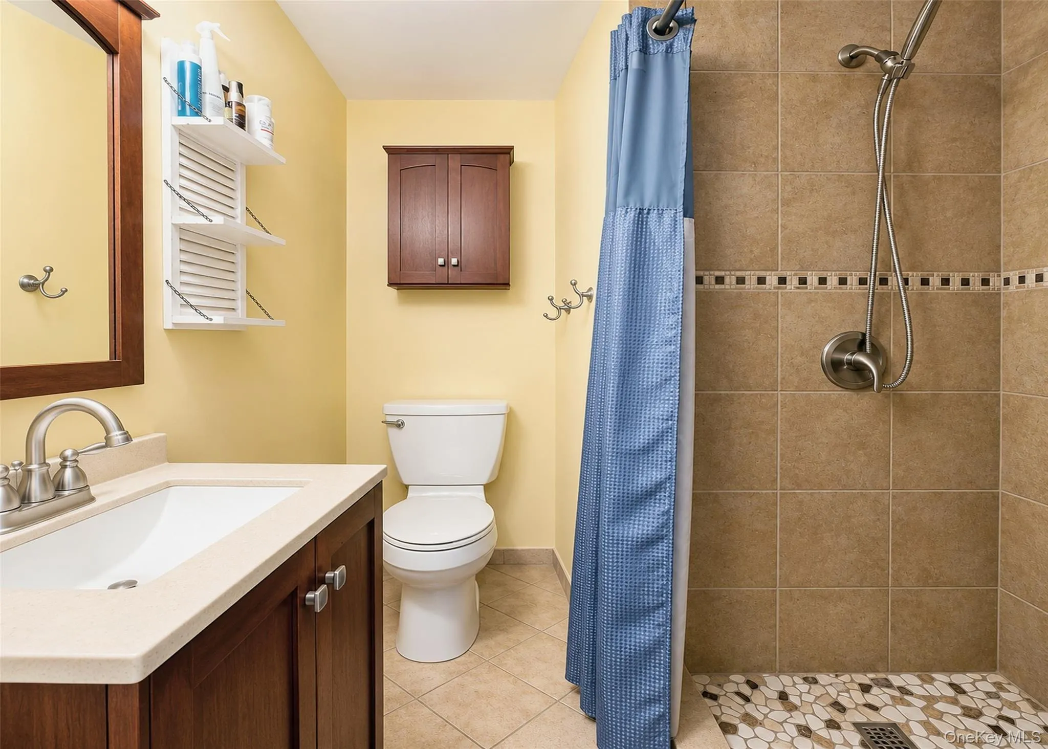 Bathroom featuring a wood-finish vanity with a light-toned countertop, an integrated sink, and a framed mirror Bathroom featuring a wood-finish vanity with a light-toned countertop, an integrated sink, and a framed mirror