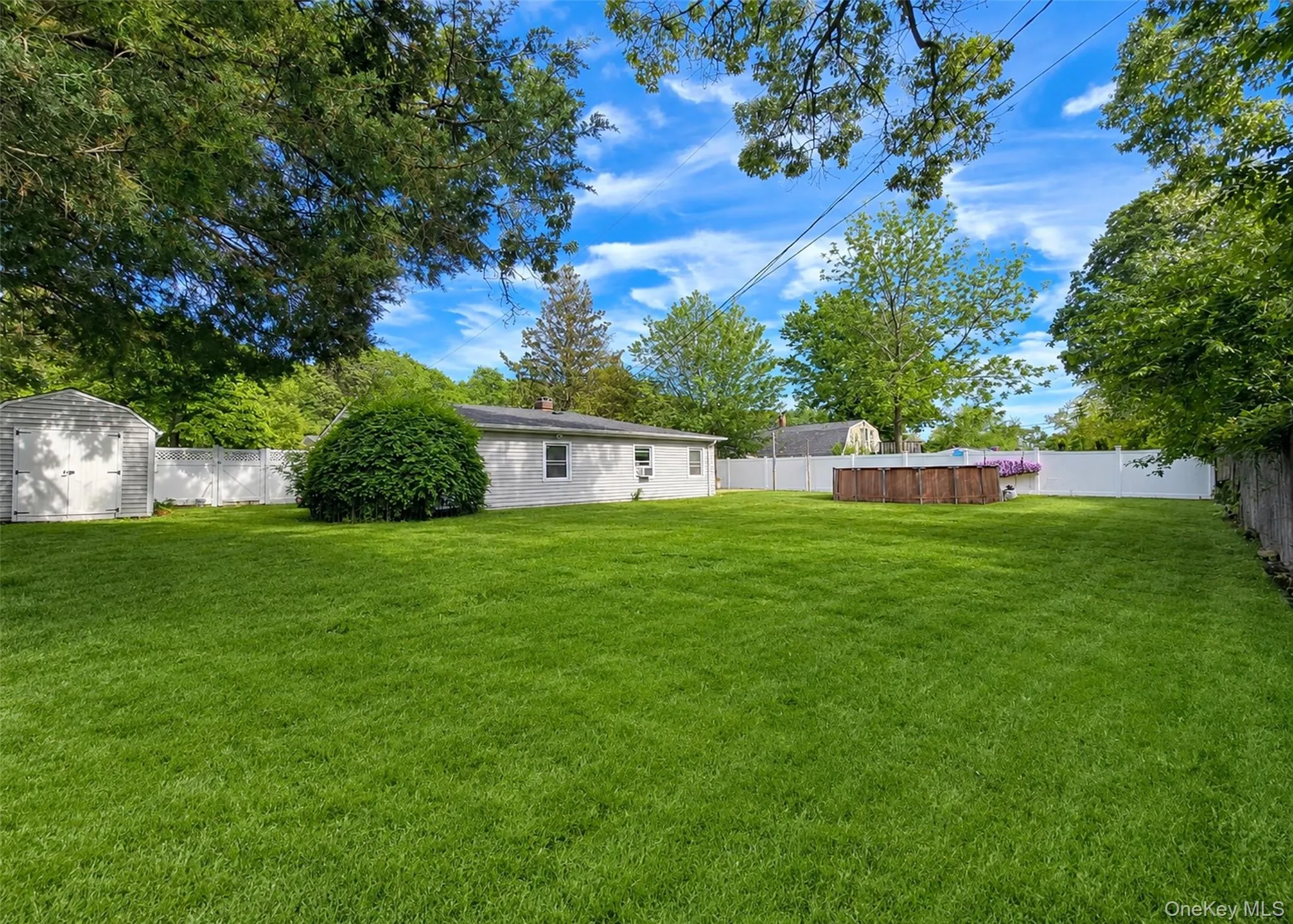 Expansive lawn featuring a privacy fence, mature perimeter trees, and a freestanding shed Expansive lawn featuring a privacy fence, mature perimeter trees, and a freestanding shed