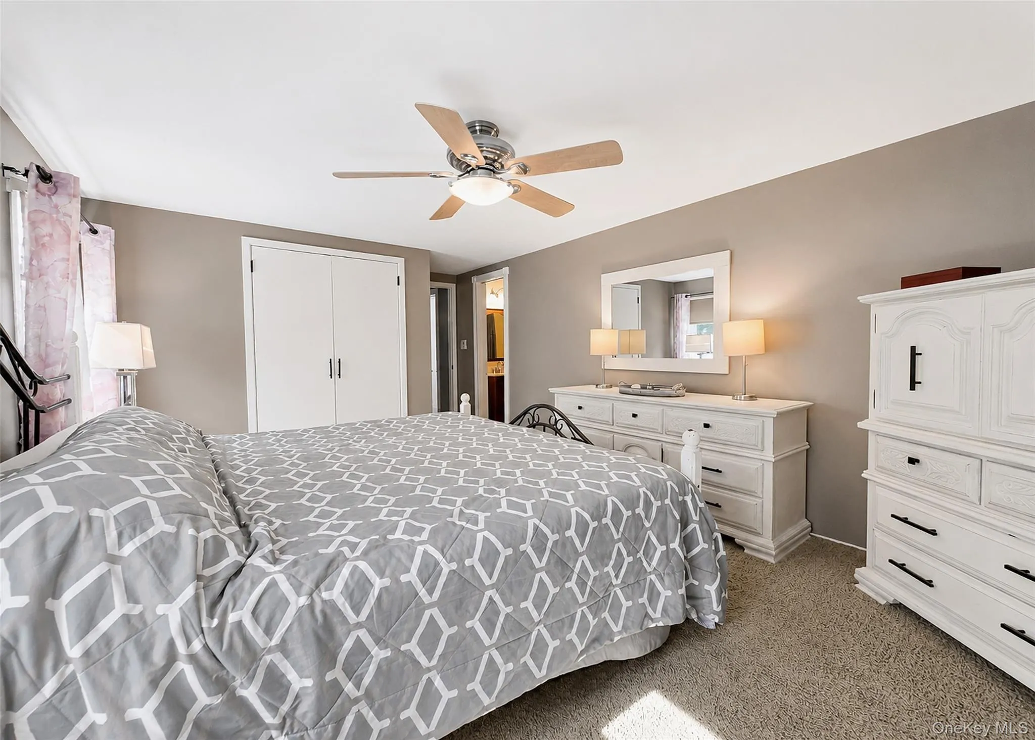Carpeted bedroom featuring a ceiling fan with integrated lighting, neutral wall tones, and white bi-fold closet doors Carpeted bedroom featuring a ceiling fan with integrated lighting, neutral wall tones, and white bi-fold closet doors